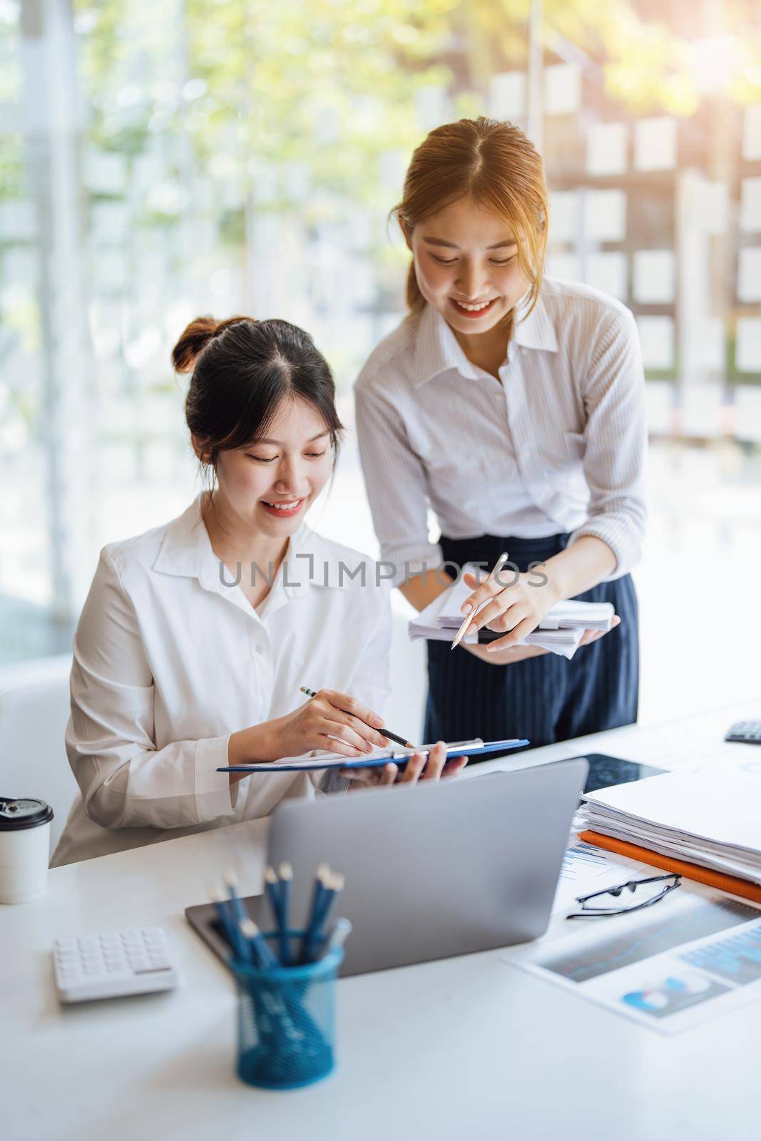 Negotiation, Analysis, Discussion: Portrait of an Asian woman economist and marketer pointing to a financial data sheet to plan investments to prevent risks and losses for the company by Manastrong