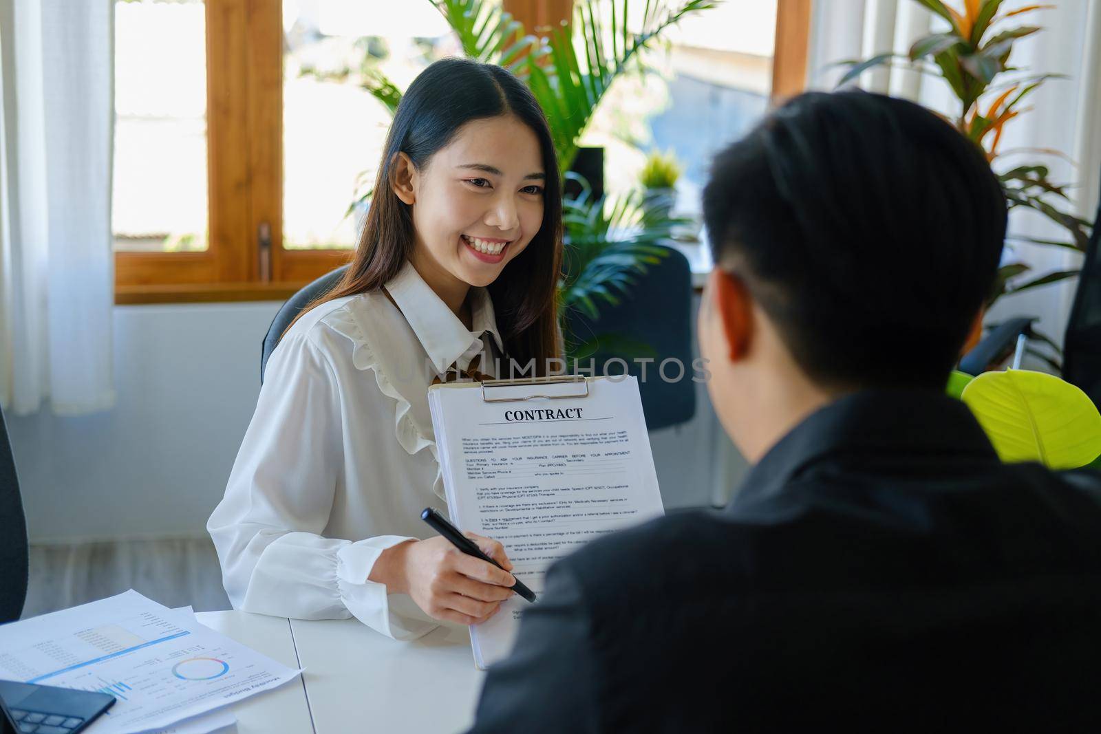 Guarantee, Mortgage, Signing, Insurance, Portrait of an agent or bank employee Asian woman holding important documents for male clients to read before signing an agreement by Manastrong