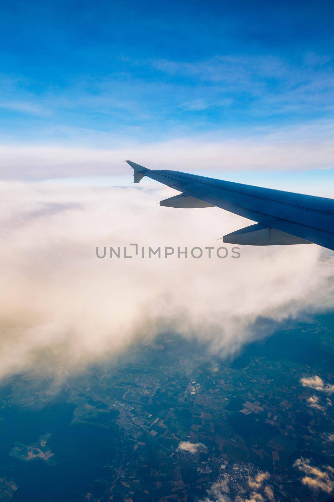 Flying and traveling, view from airplane window on the wing on sunset time. Aircraft wing under the earth and clouds. Flight in sky. Looking over aircraft wing in flight. 
