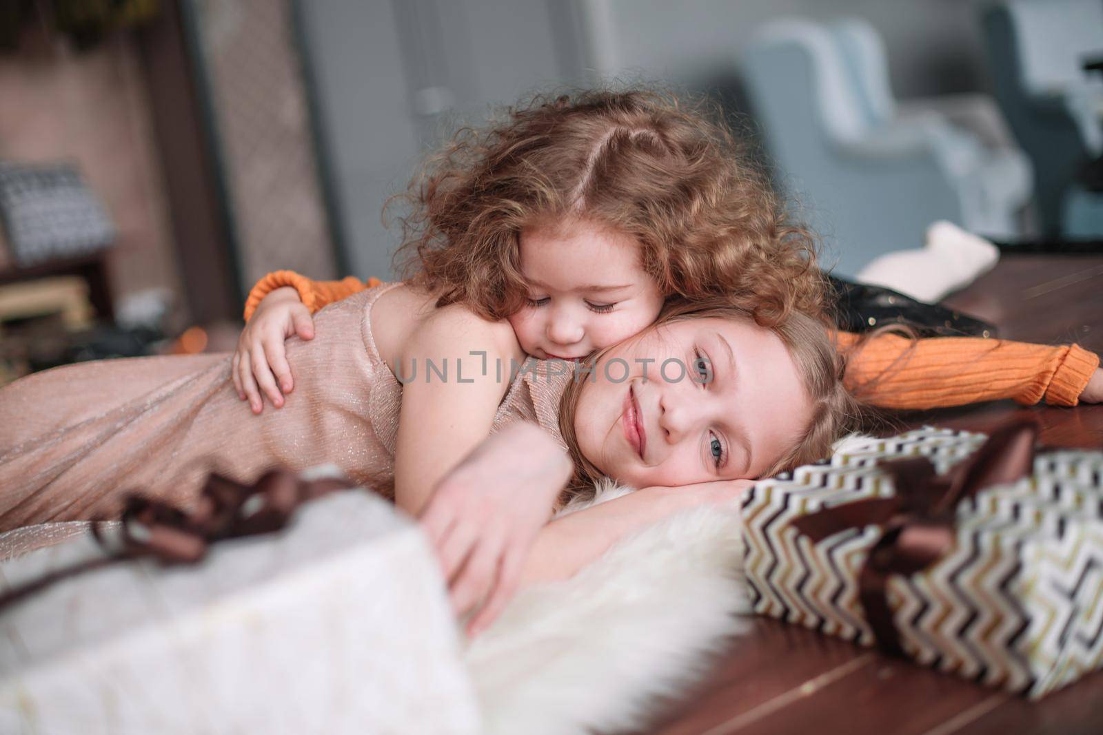 two pretty sisters are having fun in a cozy living room by SmartPhotoLab