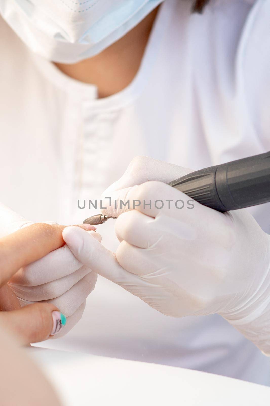 Manicure master uses an electric nail machine to remove nail polish hands in nail salon