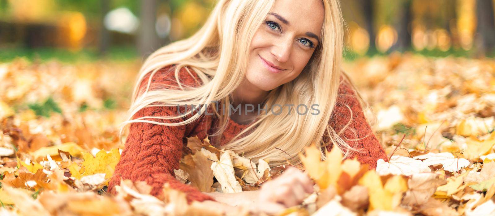 Woman lies down on leaves at the autumn park by okskukuruza