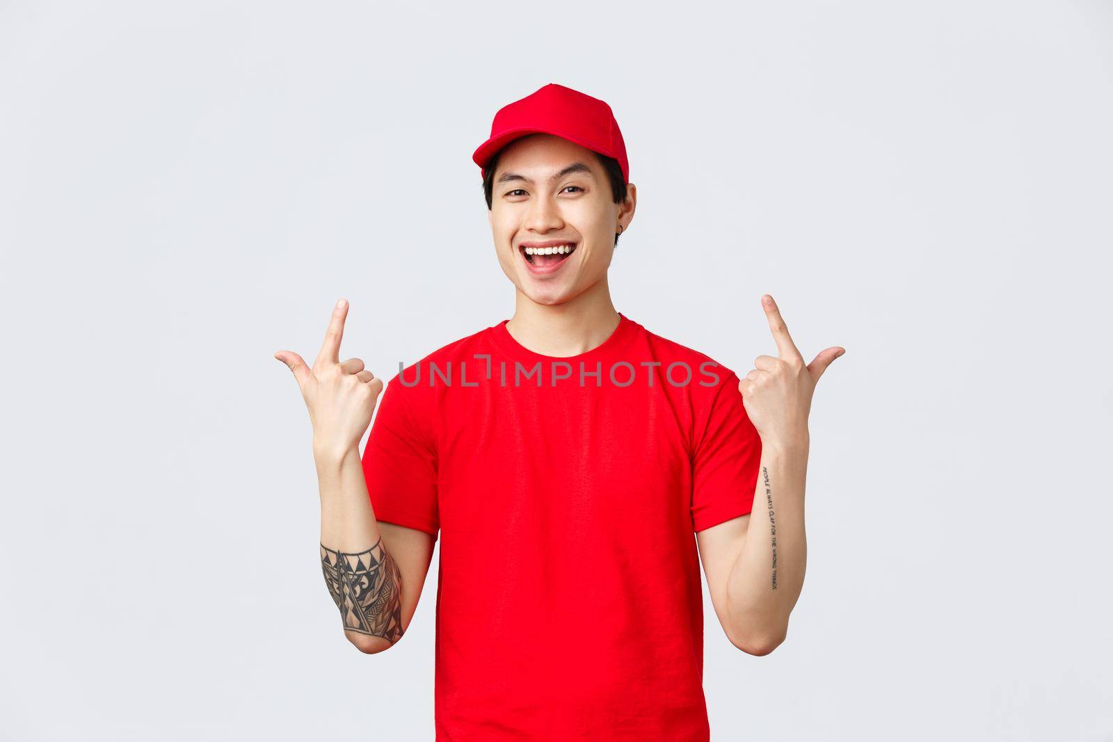Express delivery, shipping and logistics concept. Enthusiastic courier, asian guy working in delivery service, pointing fingers up and smiling upbeat, encourage make orders safely with company help.