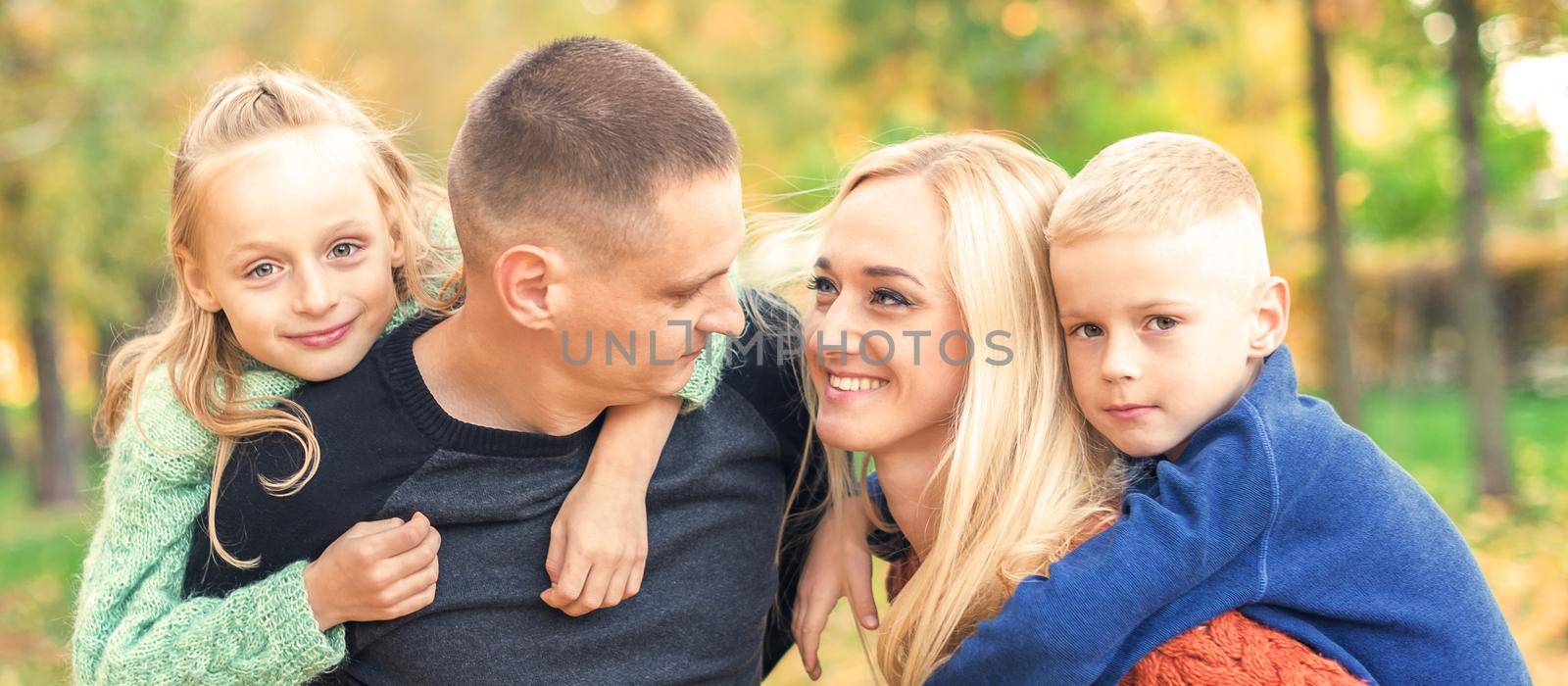 Portrait of young family playing in autumn park. Parents with children resting in the autumn park