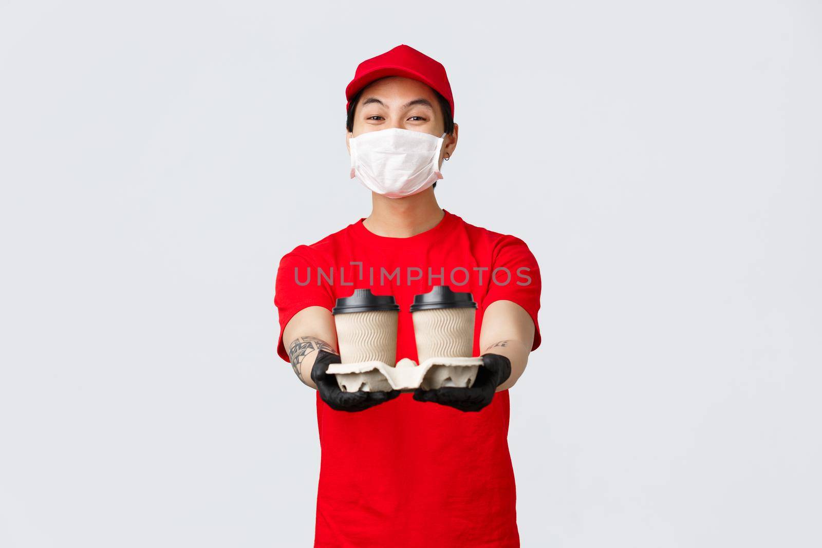 Friendly smiling asian delivery man working during covid 19 pandemic, bring your food order doorstep, extend hands with coffee from local cafe you ordered application or online.