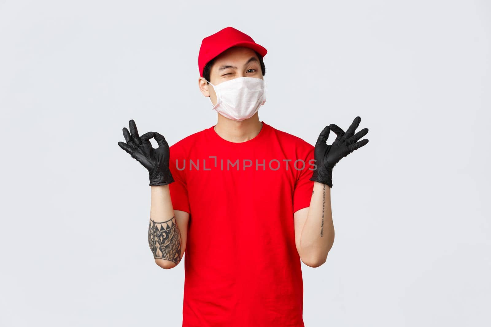 Keep calm and rely on our deliver company. Cheerful relaxed asian delivery guy in red cap and t-shirt, show zen, nirvana gesture and wink, assure your package safe. Courier stay peaceful.
