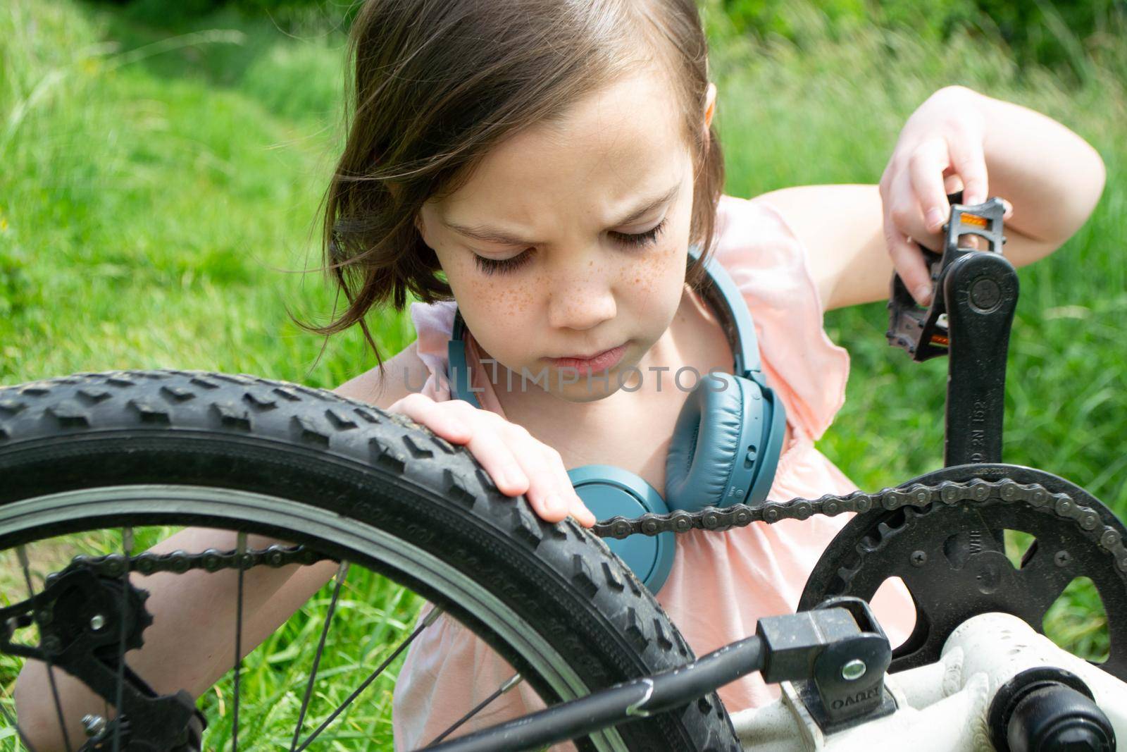 a child girl has damaged a bicycle wheel and is making repairs photo without processing. High quality photo