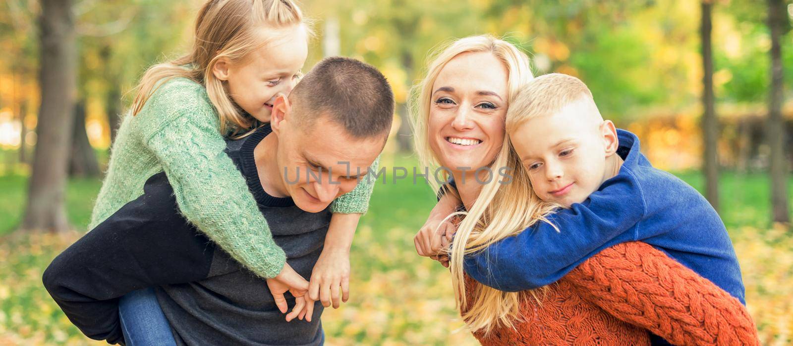 Portrait of young family playing in autumn park. Parents with children resting in the autumn park