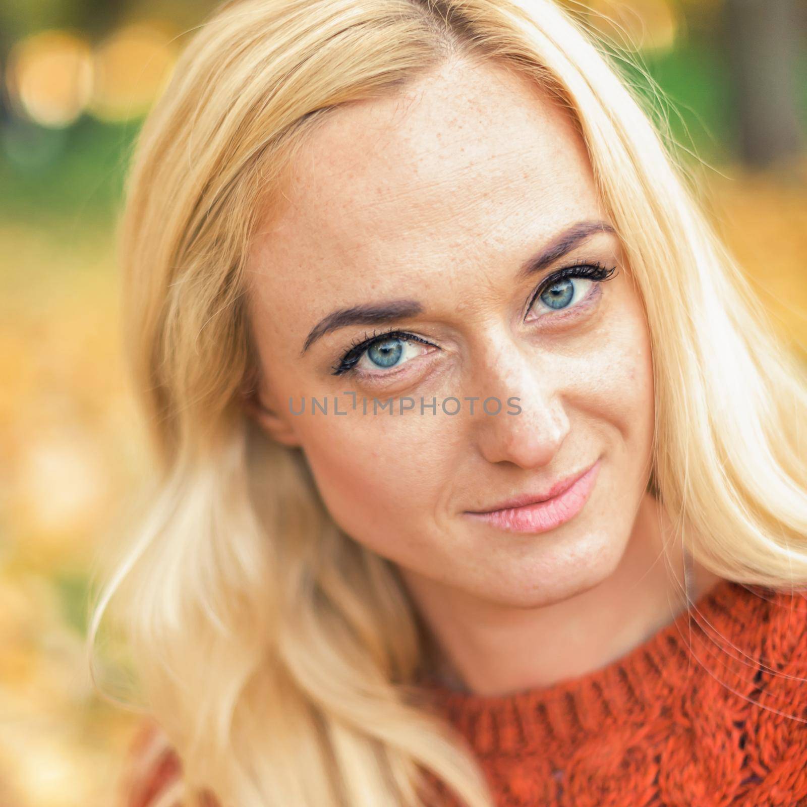 Portrait of beautiful young blond hair caucasian woman looking at camera at the Autumn Park