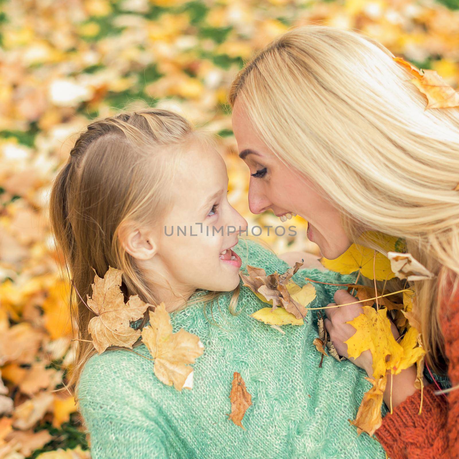 Beautiful young caucasian mother playing with her little child in the autumn park