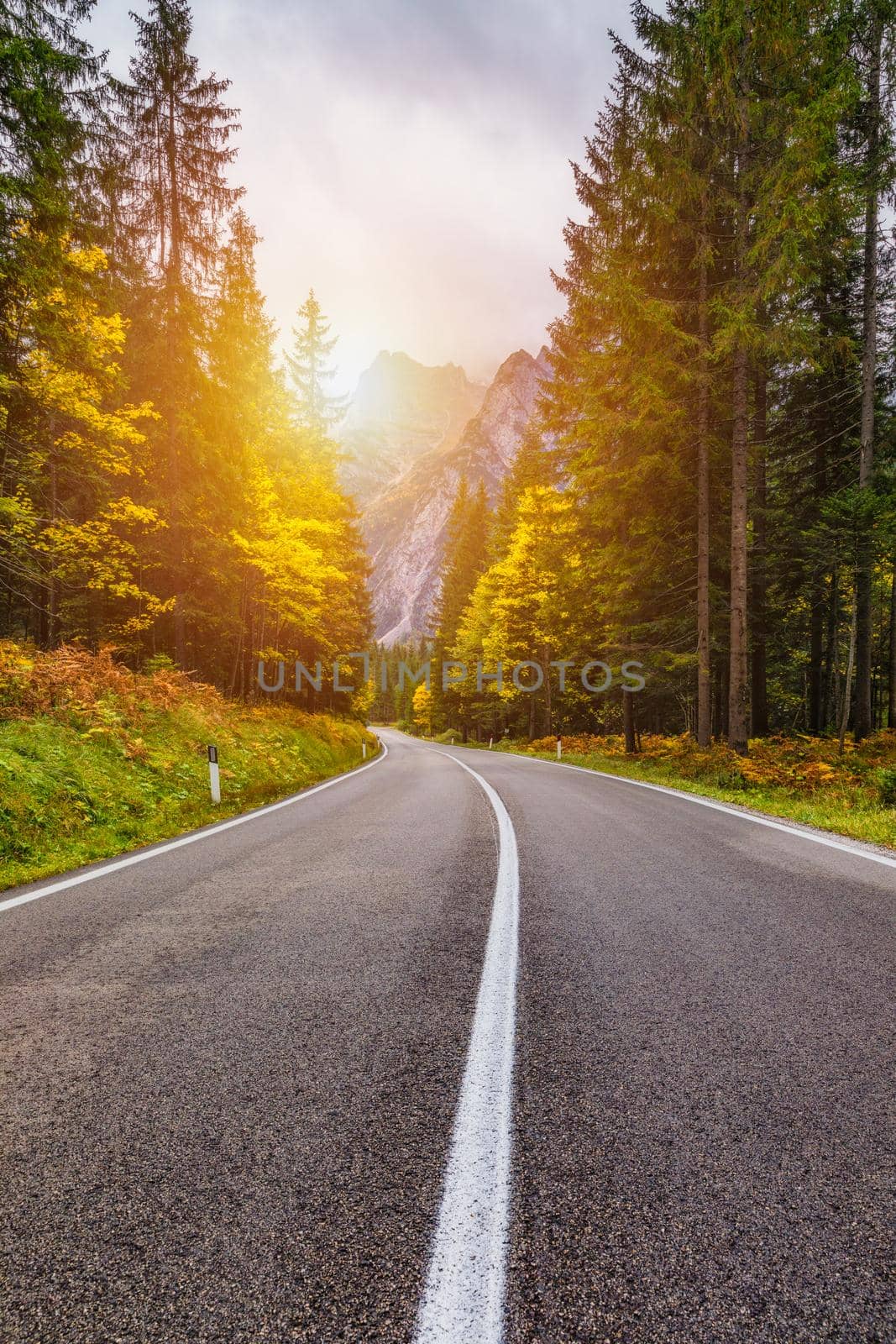 Mountain road. Landscape with rocks, sunny sky with clouds and beautiful asphalt road in the evening in summer. Vintage toning. Travel background. Highway in mountains.  