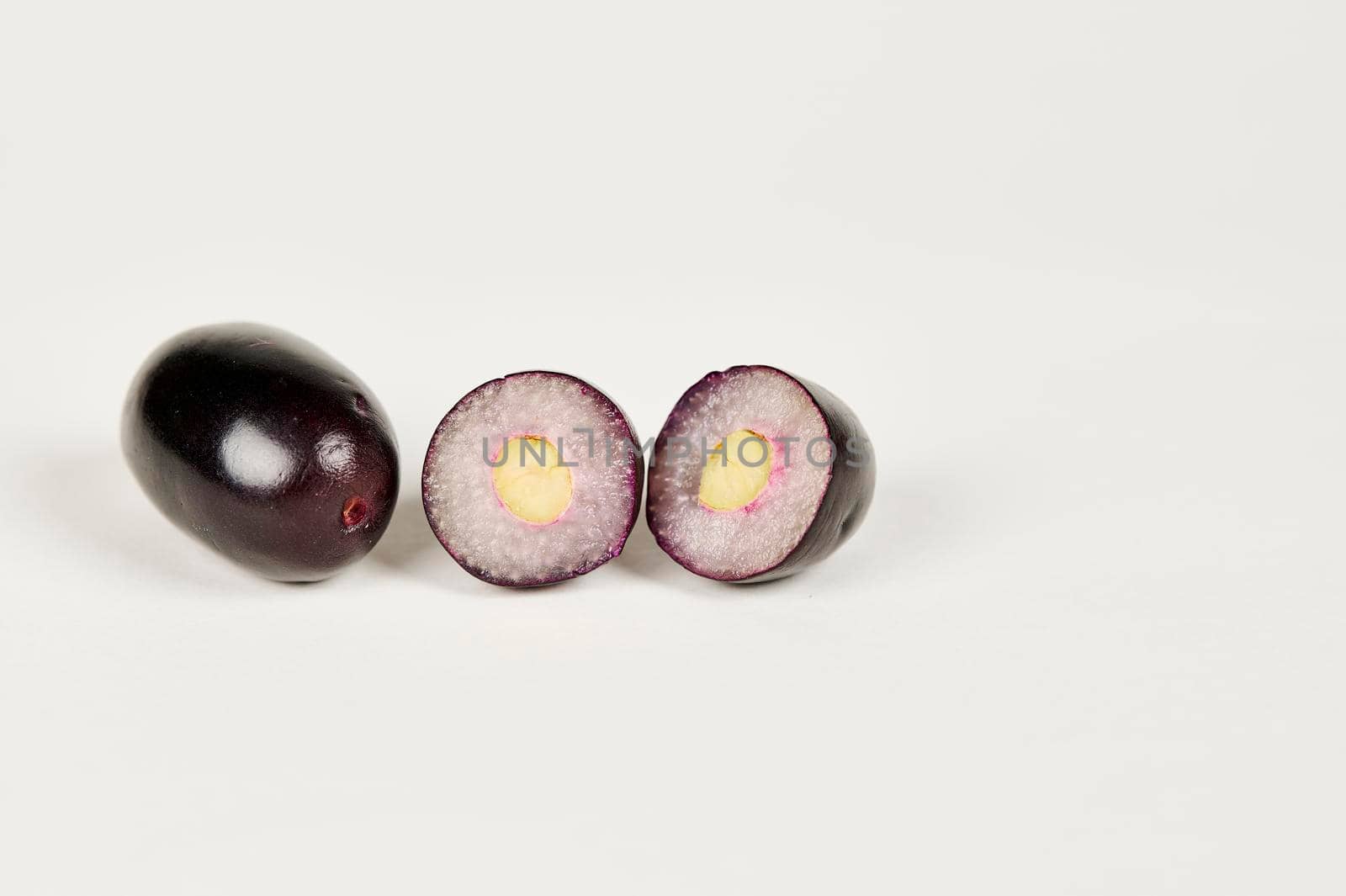 Whole and cut Jambolan plum or Java Plum or Jamun fruit on a white background