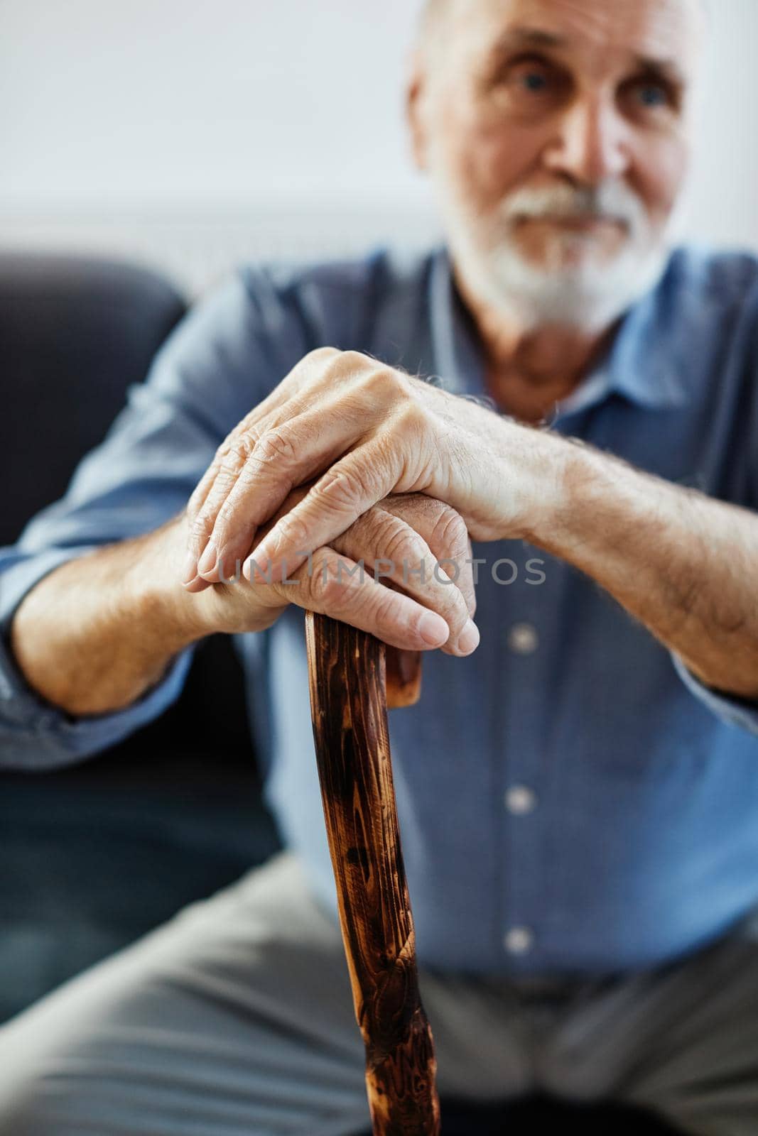 Portrait of a disabled senior man with a walking cane stick at home