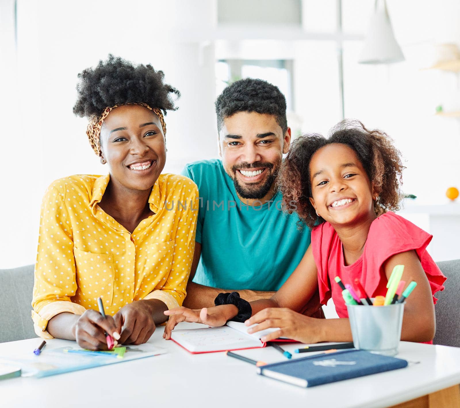 father and mother teaching daughter and helping with homework at home