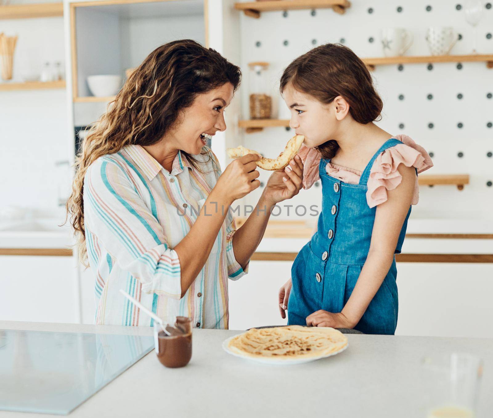 Family preparing and eating pancakes in the kitchen at home