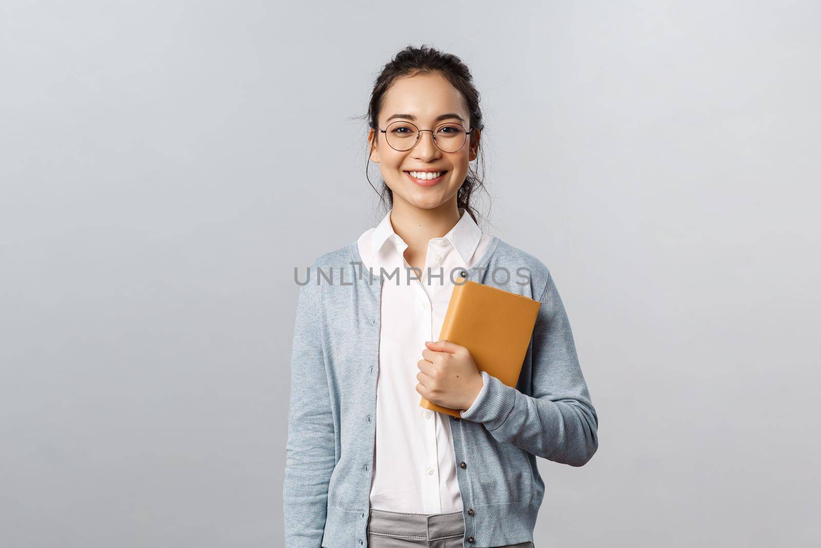 Education, teachers, university and schools concept. Young smiling woman, employer or student in glasses, holding planner, writing down business meetings in notebooks, prepare schedule by Benzoix