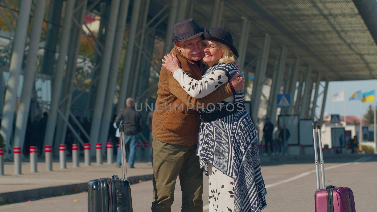 Elderly old grandmother grandfather retirees tourists reunion in airport terminal after long separation traveling. Lovely senior couple husband and wife happily hugging meeting after business trip