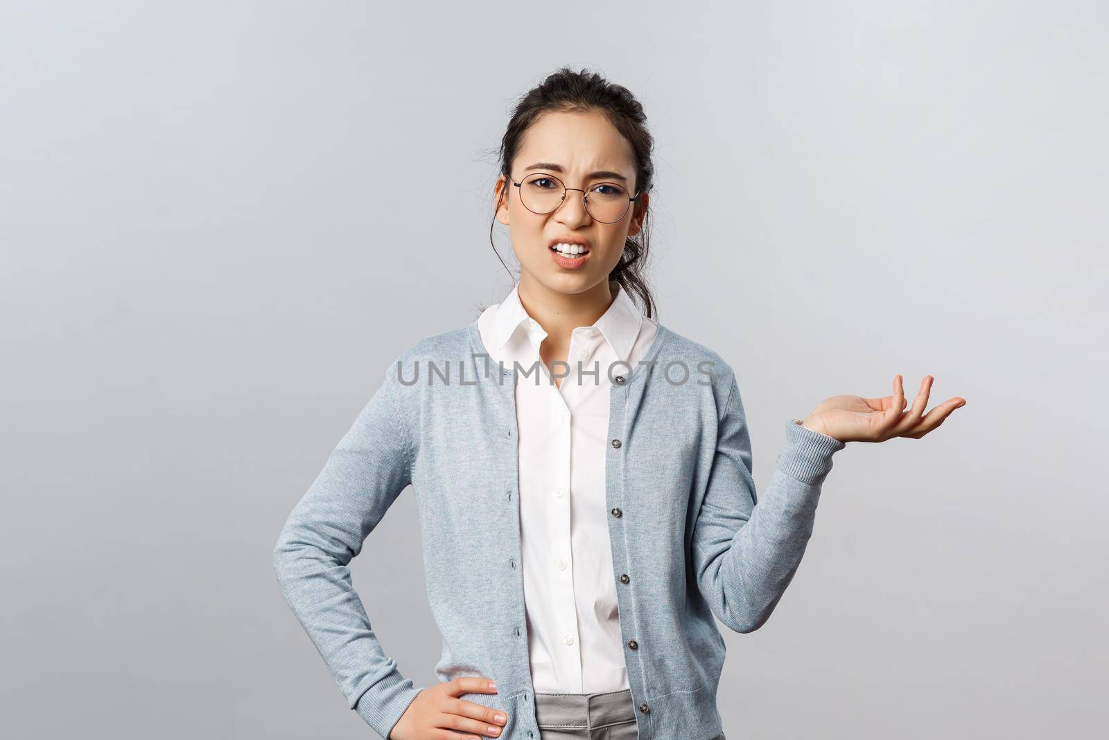 So what. Skeptical arrogant asian woman, looking with dismay and judgement camera, raise hand sideways and shrugging unbothered, look frustrated at something awful and bad, grey background by Benzoix
