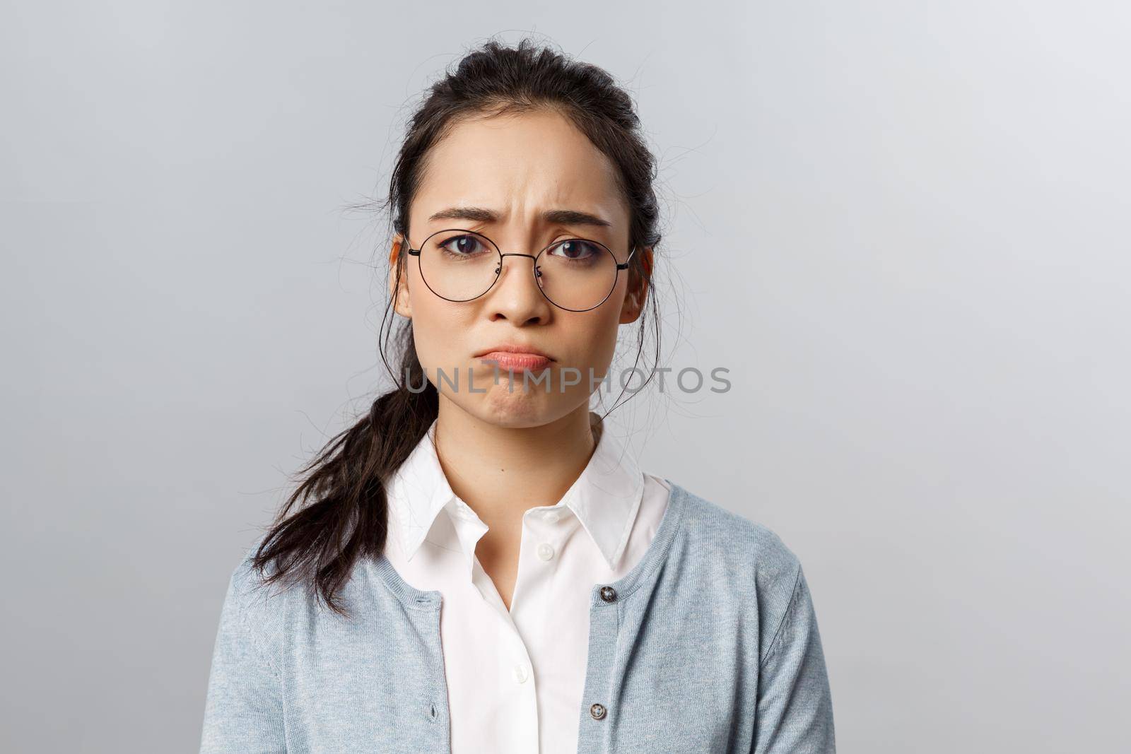 Close-up portrait of gloomy, upset and disappointed young asian female facing failure, losing, regret mjssing interesting event, pouting and sob, frowning camera standing grey background by Benzoix