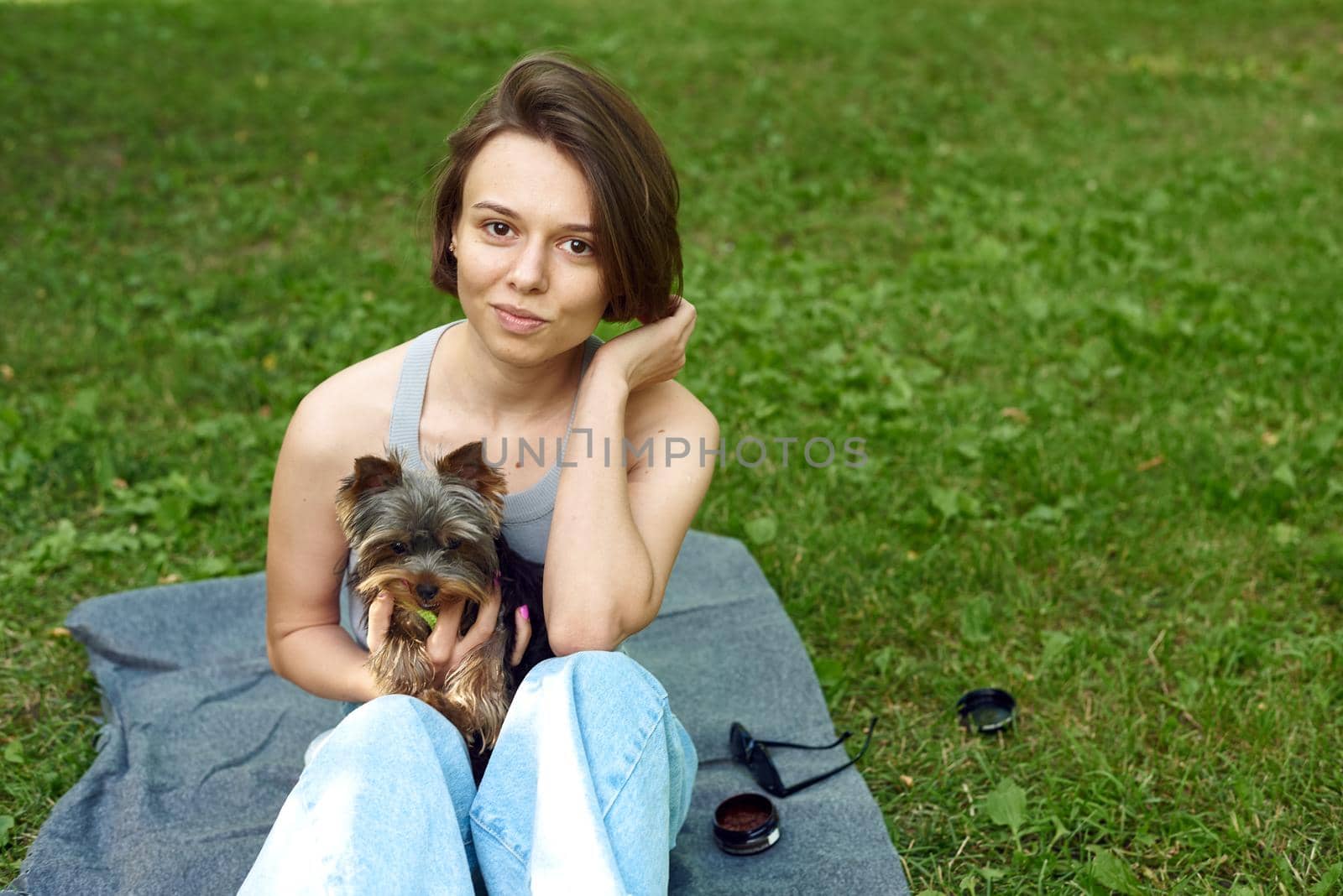 A cute girl with a square hugs a Yorkshire terrier on the street. Hugs with your little dog in the park.