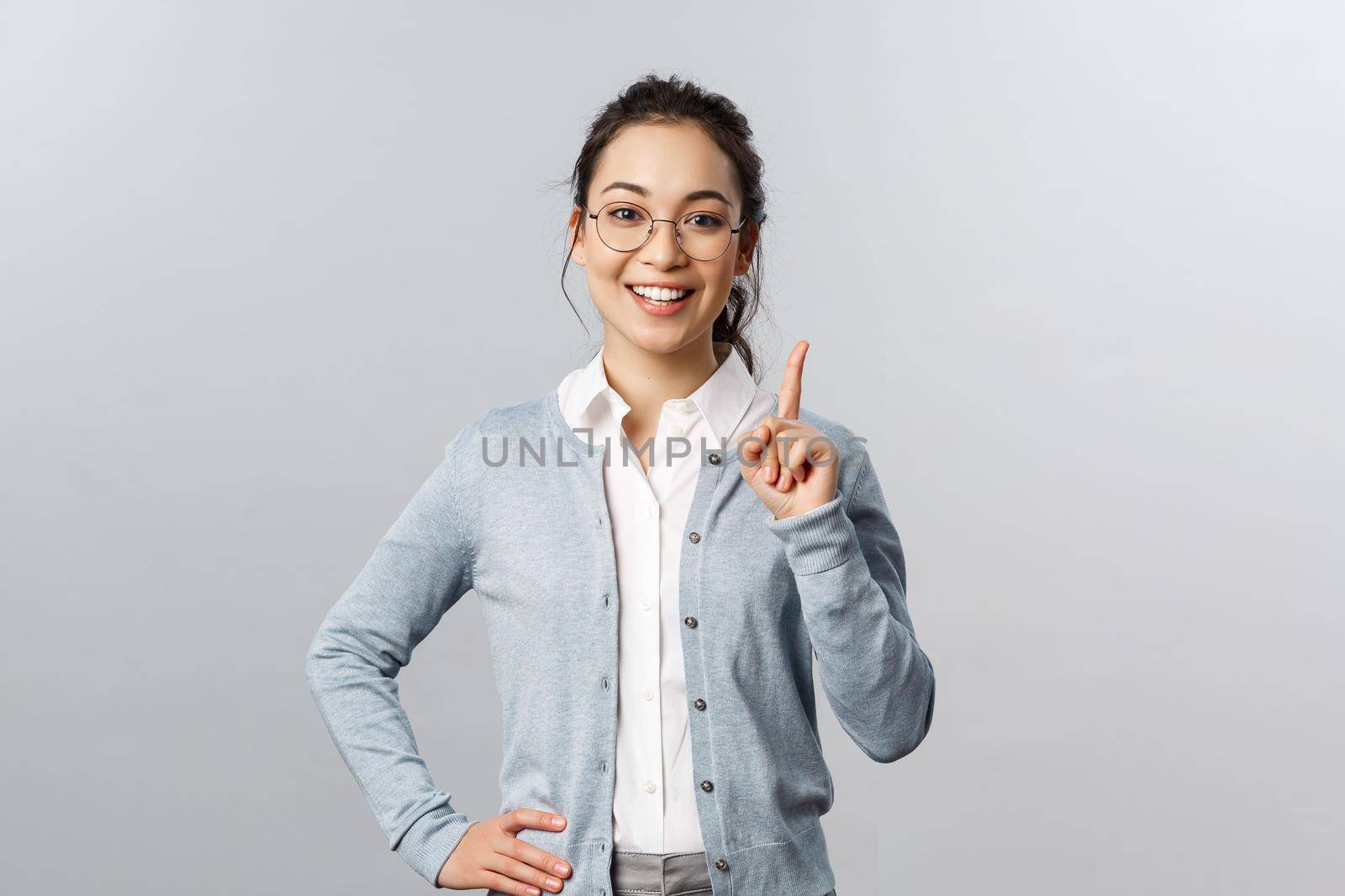 Education, studying and online classes concept. Rule number one. Cheerful pretty asian girl explaining exercise to class, raising index finger, pointing up, add a suggestion or making point, smile by Benzoix