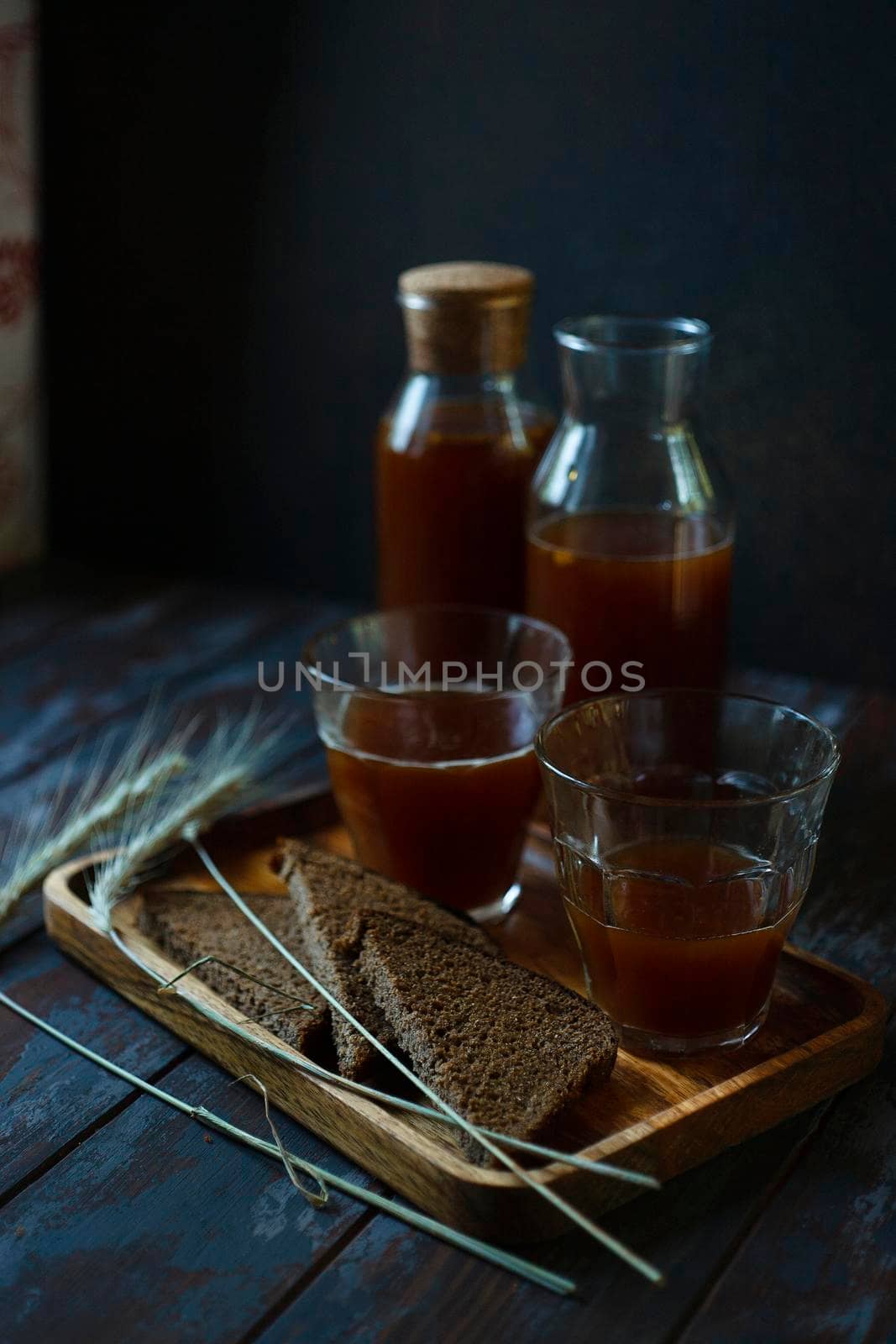 Two bottles and two glasses with traditional homemade beverage kvass in glass and bottles is a good summer cooling drink on dark blue background, selective focus.
