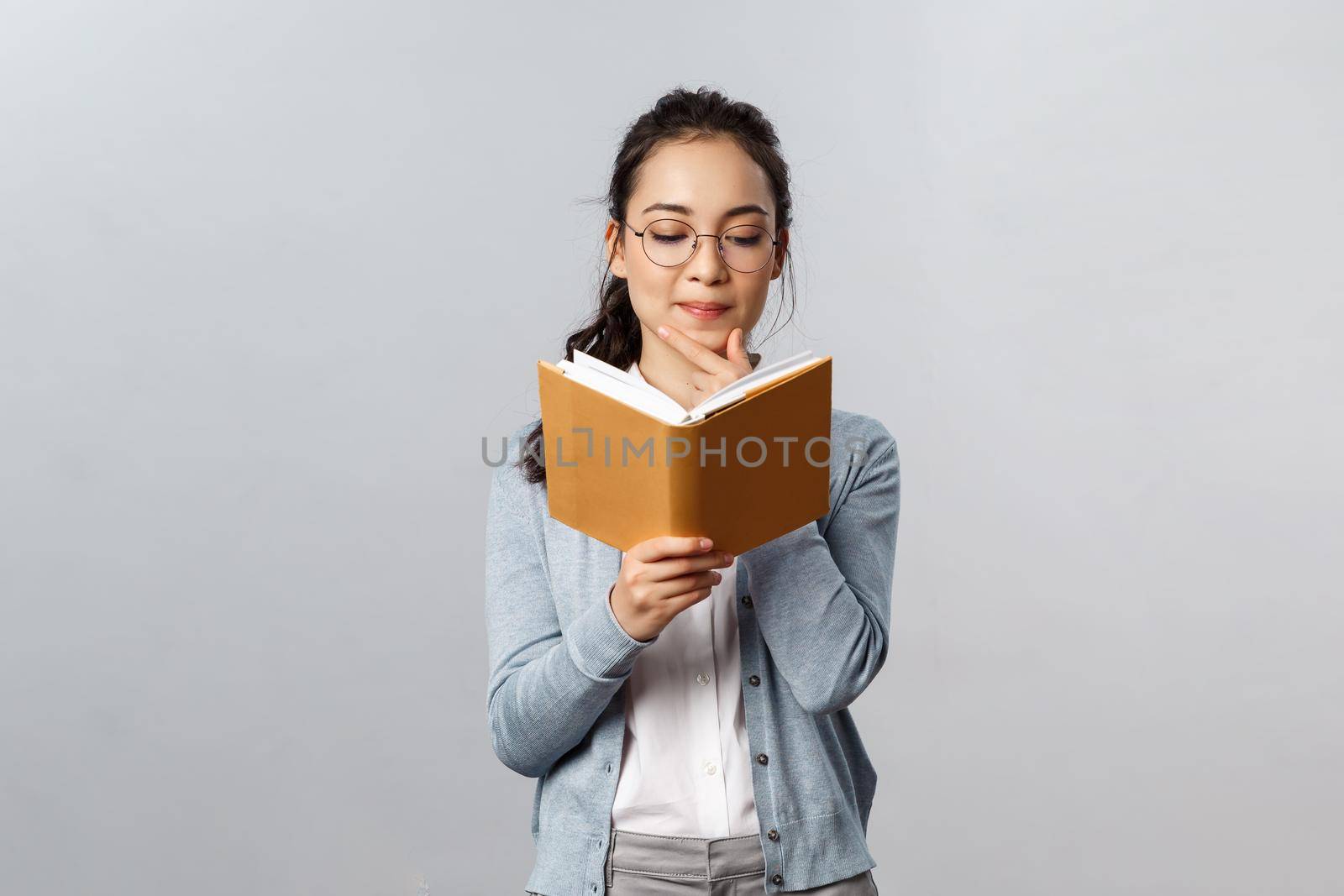 Education, teachers, university and schools concept. Intrigued smart good-looking asian student prepare for test exam, reading her lecture notes in notebooks, checking schedule in planner, thoughtful.