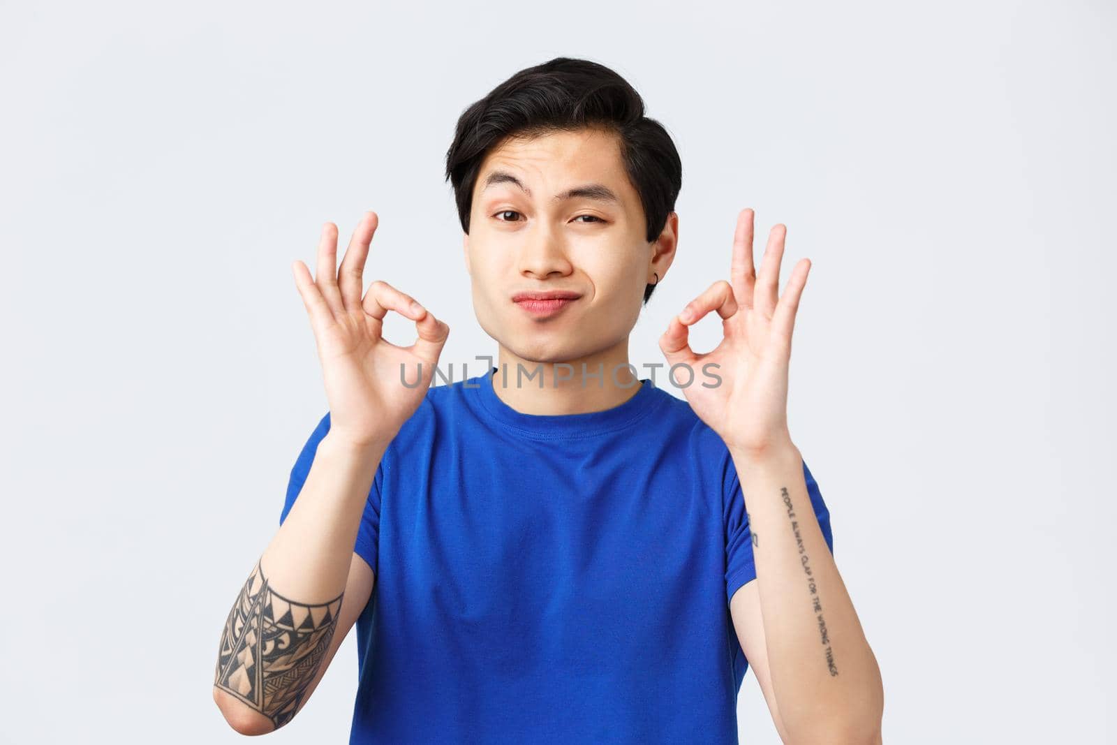 Lifestyle, people emotions and beauty concept. Satisfied and totally pleased asian man showing okay perfection gesture and smile impressed, tasted fantastic tasty food, grey background.