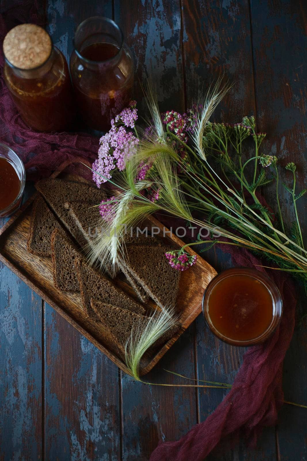 Traditional homemade beverage kvass in glasses and bottles with summer bouqute of rye and yarrow, flat lay with copy space, selective focus.