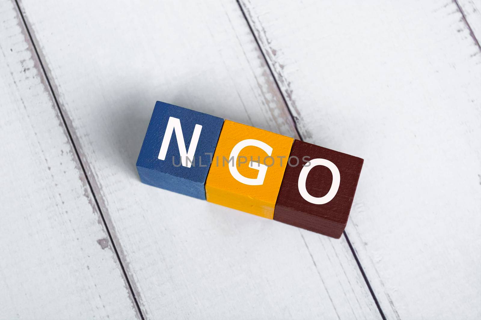 NGO acronym for Non-Governmental Organization on colorful wooden cube. Flat lay. Copy Space. Directly above.