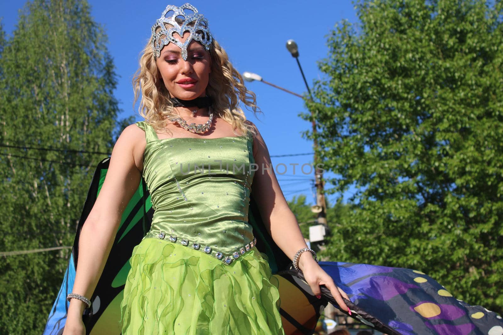 Beautiful blonde in a butterfly costume on stilts. Carnival. The concept of LGBTQ..