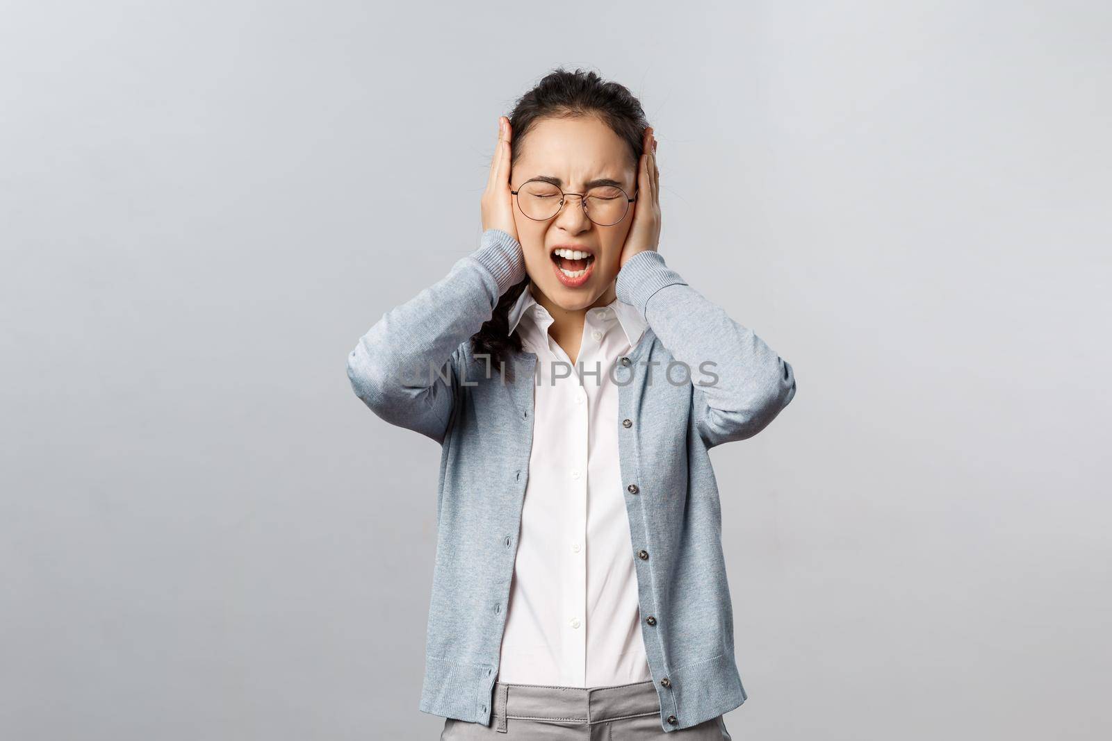 People, emotions and lifestyle concept. Stop it, cant bear listen to you anymore. Depressed young fed-up asian woman scream from discomfort and annoyance, shut ears not hear noisy annoying sound.