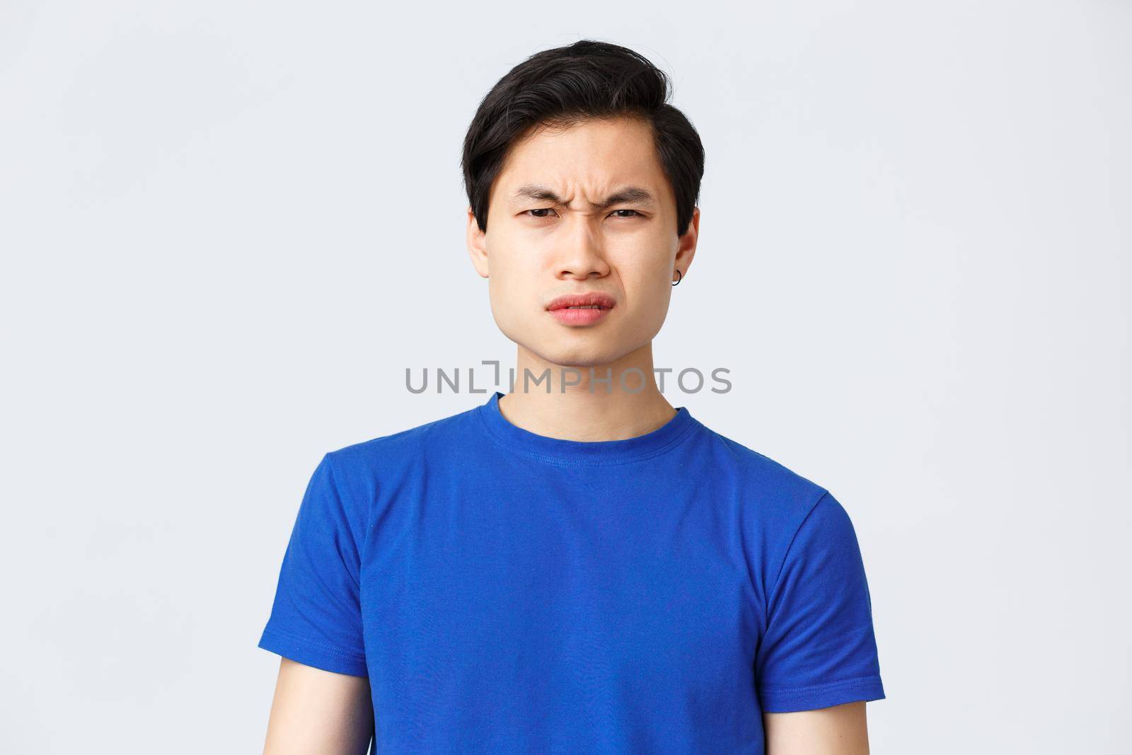 Lifestyle, people emotions and beauty concept. Wtf going on. Frustrated and puzzled asian guy in blue t-shirt frowning, grimacing confused cant understand what happened, stand grey background by Benzoix