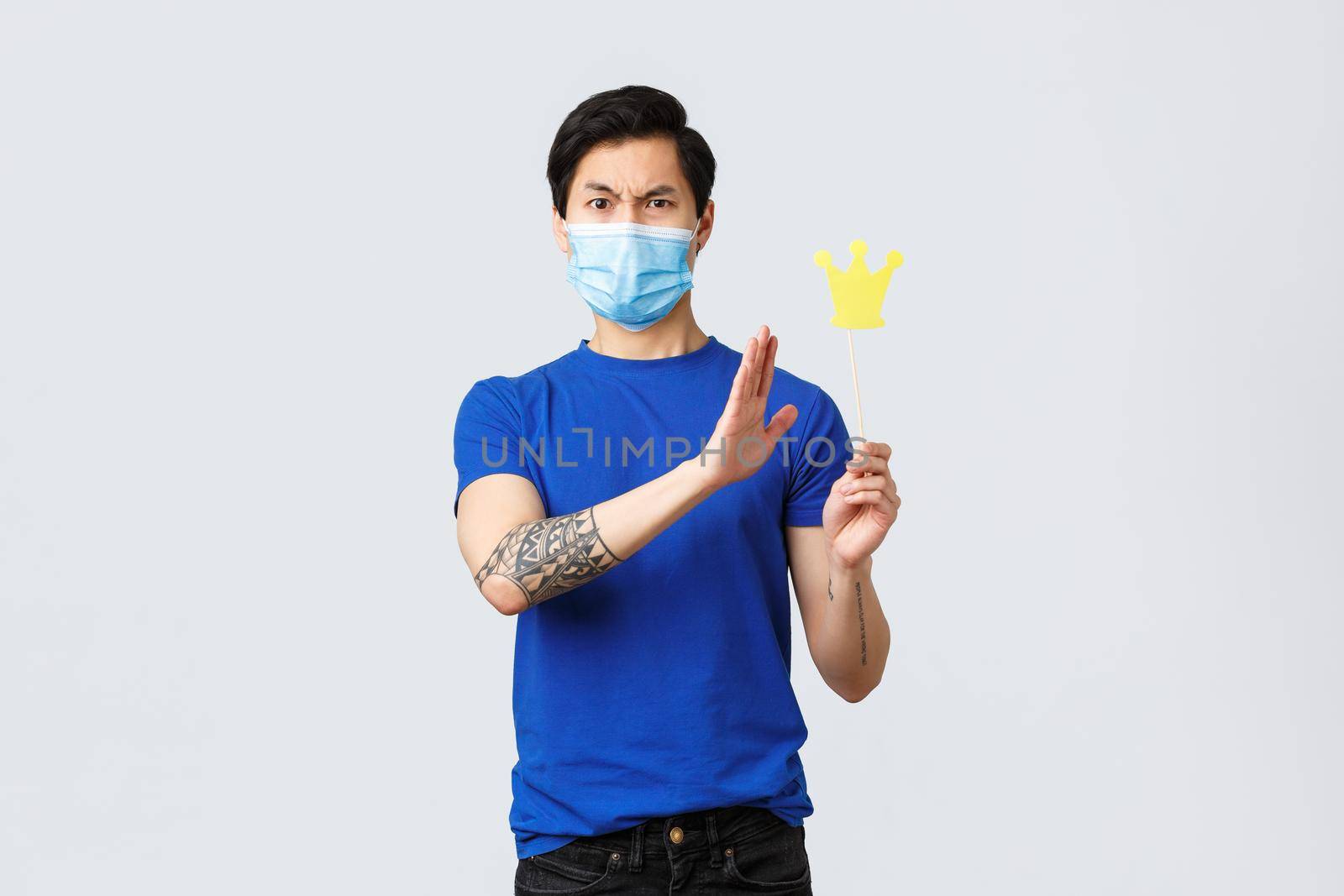 Lifestyle, people different emotions and covid-19 pandemic concept. Guy denying he is arrogant turn away from crown. Frowning insulted and wearing medical mask, grey background.