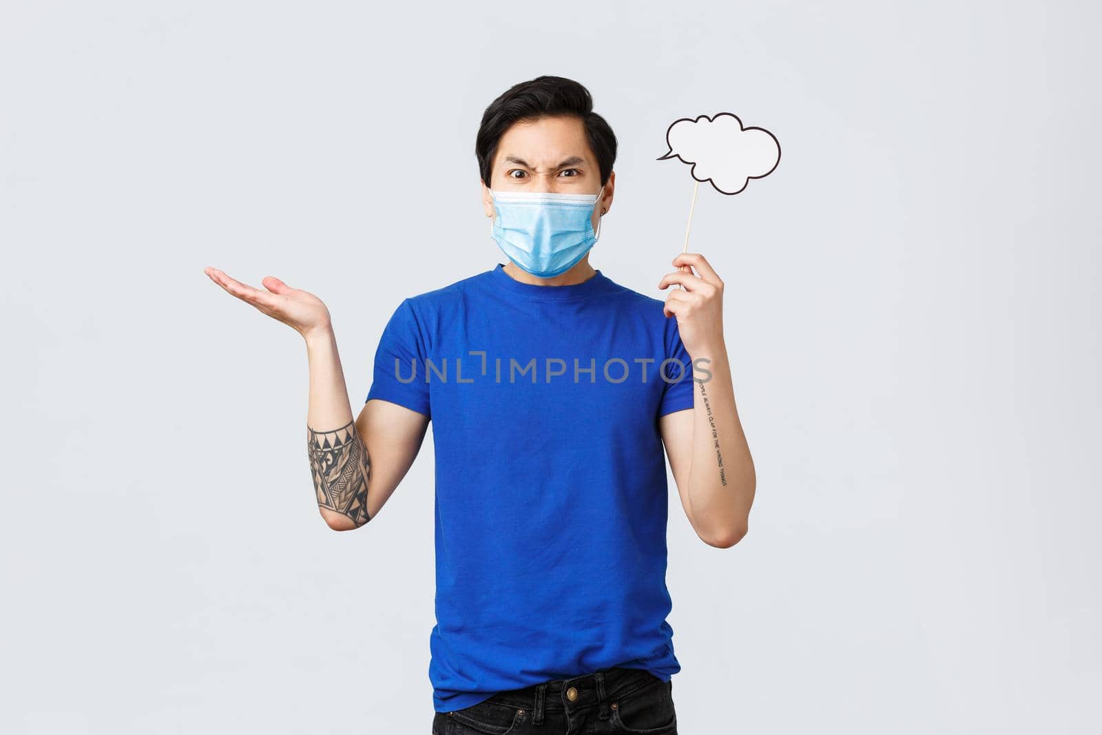 Lifestyle, people different emotions and covid-19 pandemic concept. Angry man in medical mask swearing and complaining, raise hand dismay, grimacing, holding comment cloud near head by Benzoix