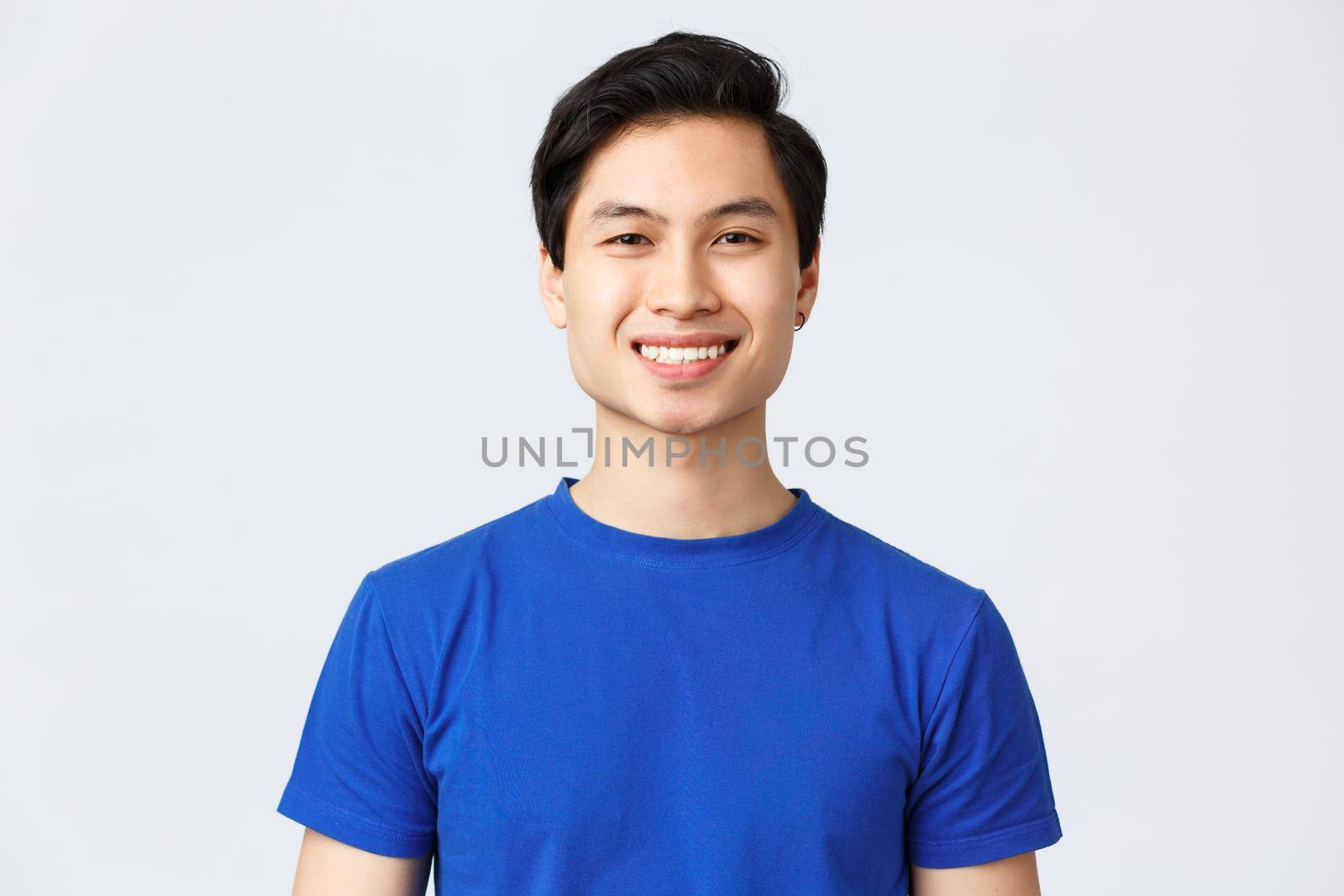 Self-quarantine, social distancine, leisure and lifestyle concept. Close-up of handsome cheerful asian man in blue t-shirt satisfied with new haircut after visiting barbershop.