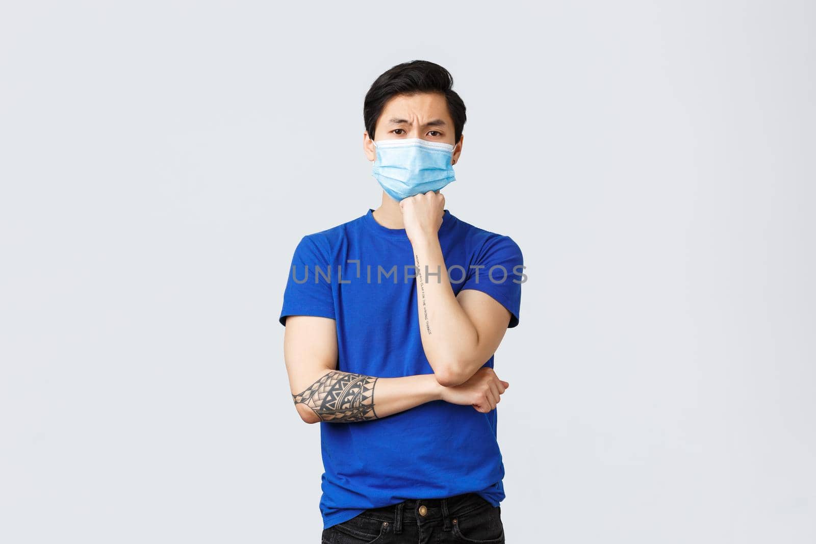 Different emotions, social distancing, self-quarantine on covid-19 and lifestyle concept. Tired and indifferent asian guy in medical mask trying concentrate on conversation, feel bored.