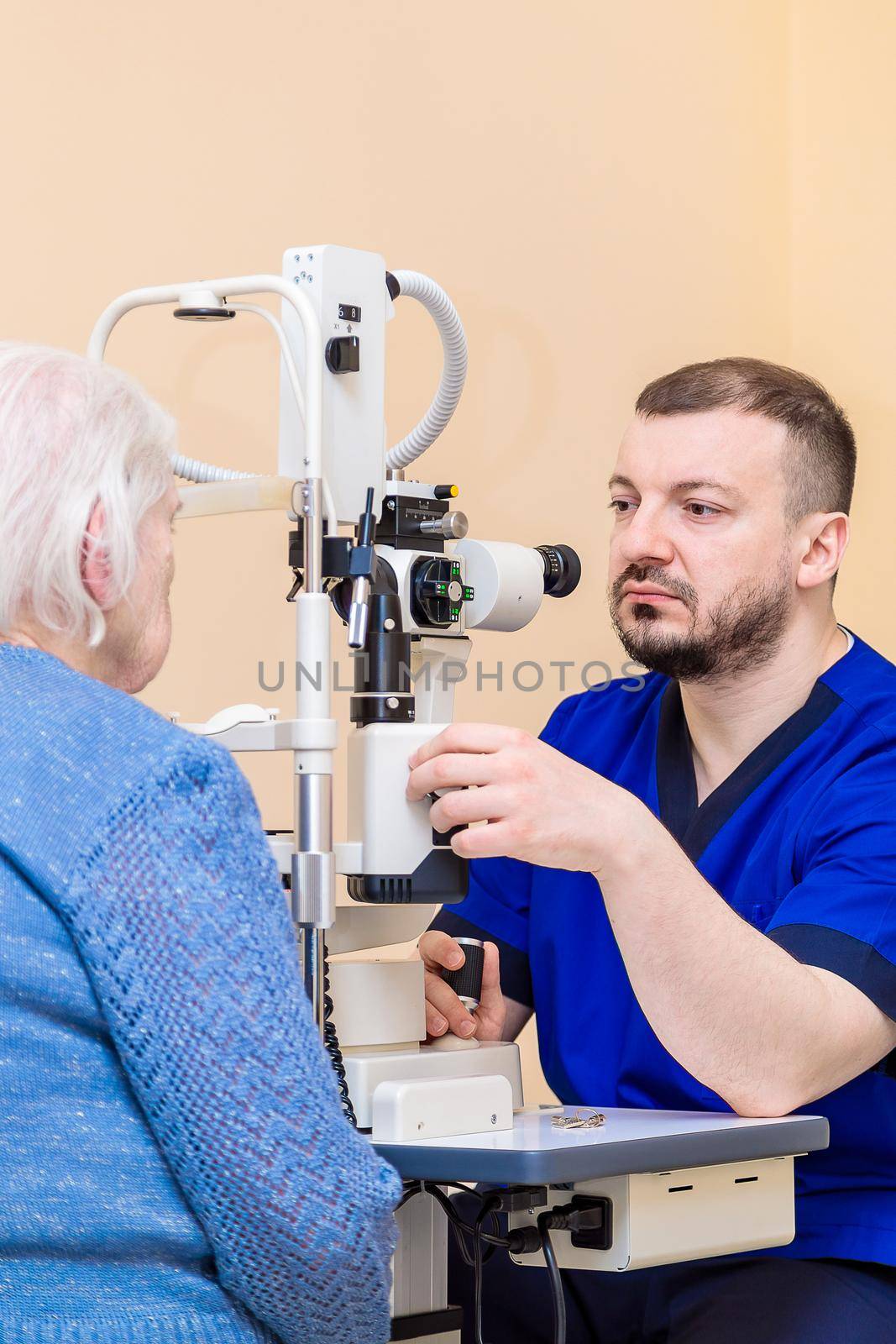 A male ophthalmologist checks the eyesight of an adult woman using a modern device with a light beam.
