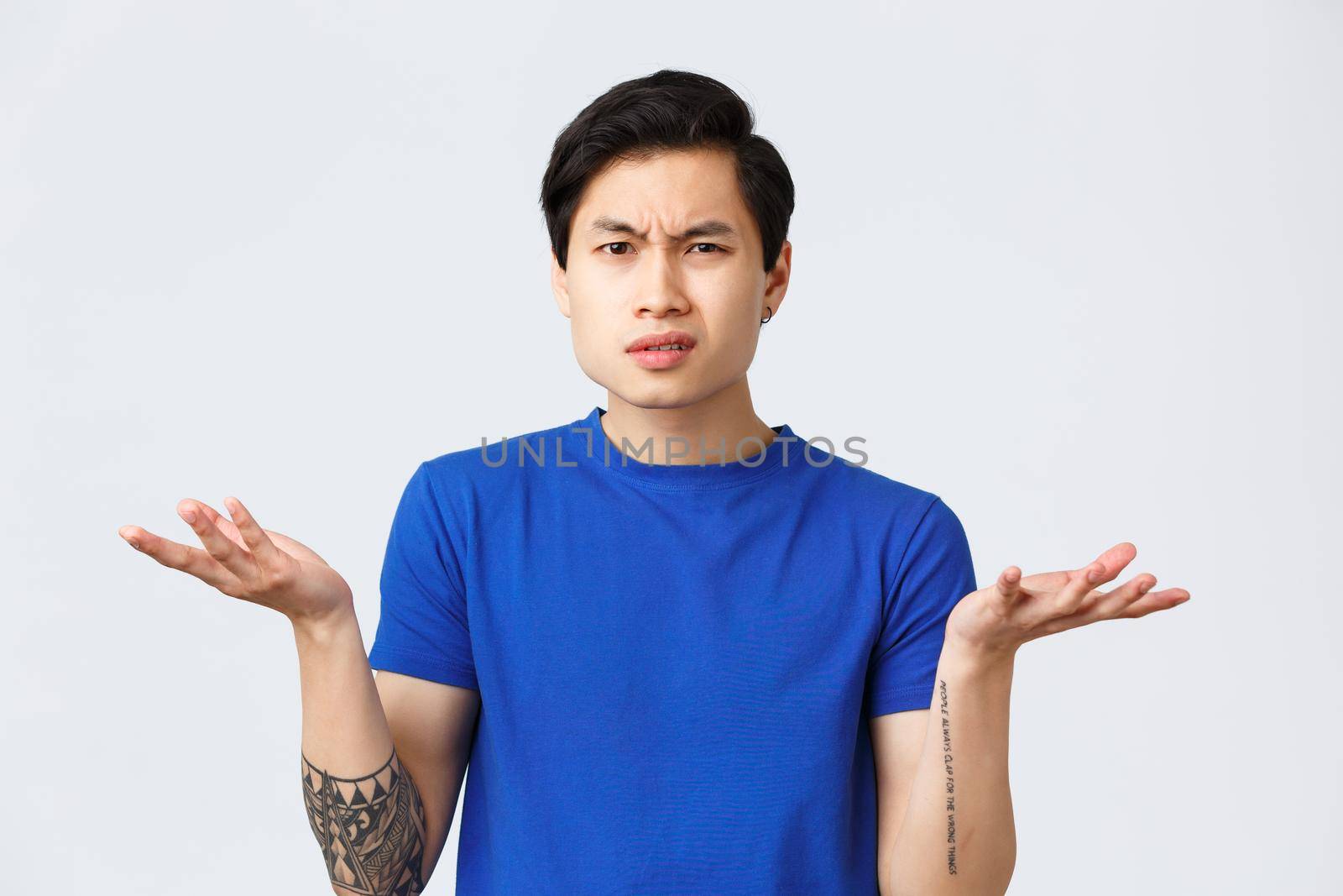 Lifestyle, people emotions and beauty concept. Confused and indecisive young asian man cant understand what happened, shrugging with hands spread and puzzled grimace,wear blue t-shirt.