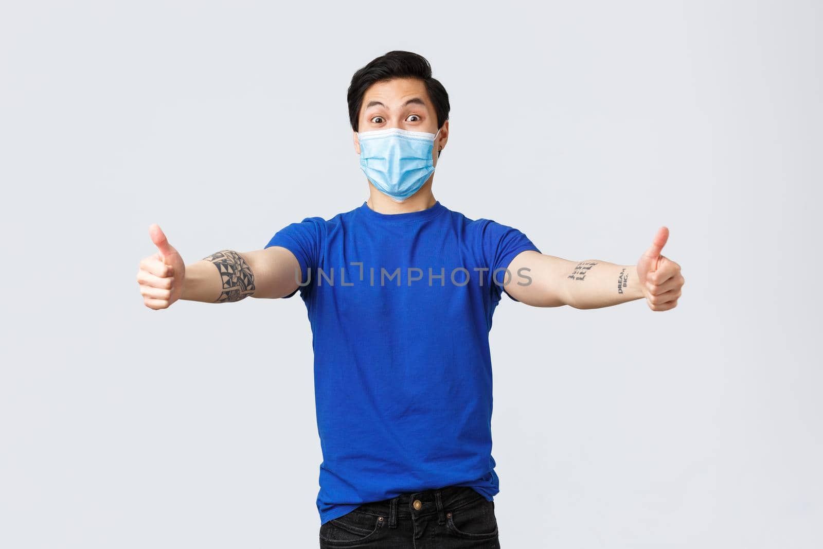 Different emotions, social distancing, self-quarantine on covid-19 and lifestyle concept. Surprised cheerful asian man in medical mask and t-shirt, reaching for hug, greeting guest by Benzoix