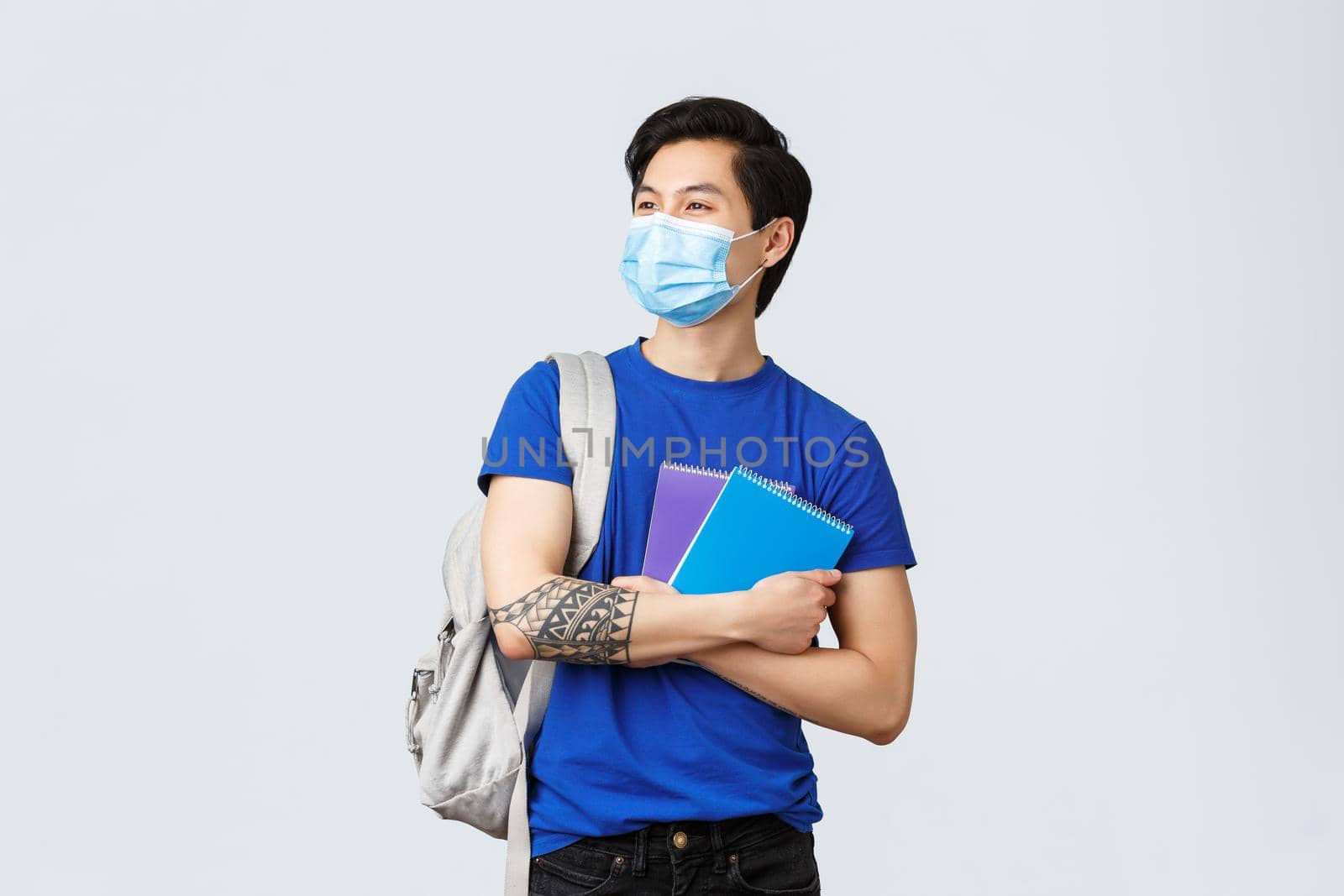 Back to school, studying during covid-19, education and university life concept. Carefree handsome asian male student, college freshman in medical mask with notebooks and backpack.