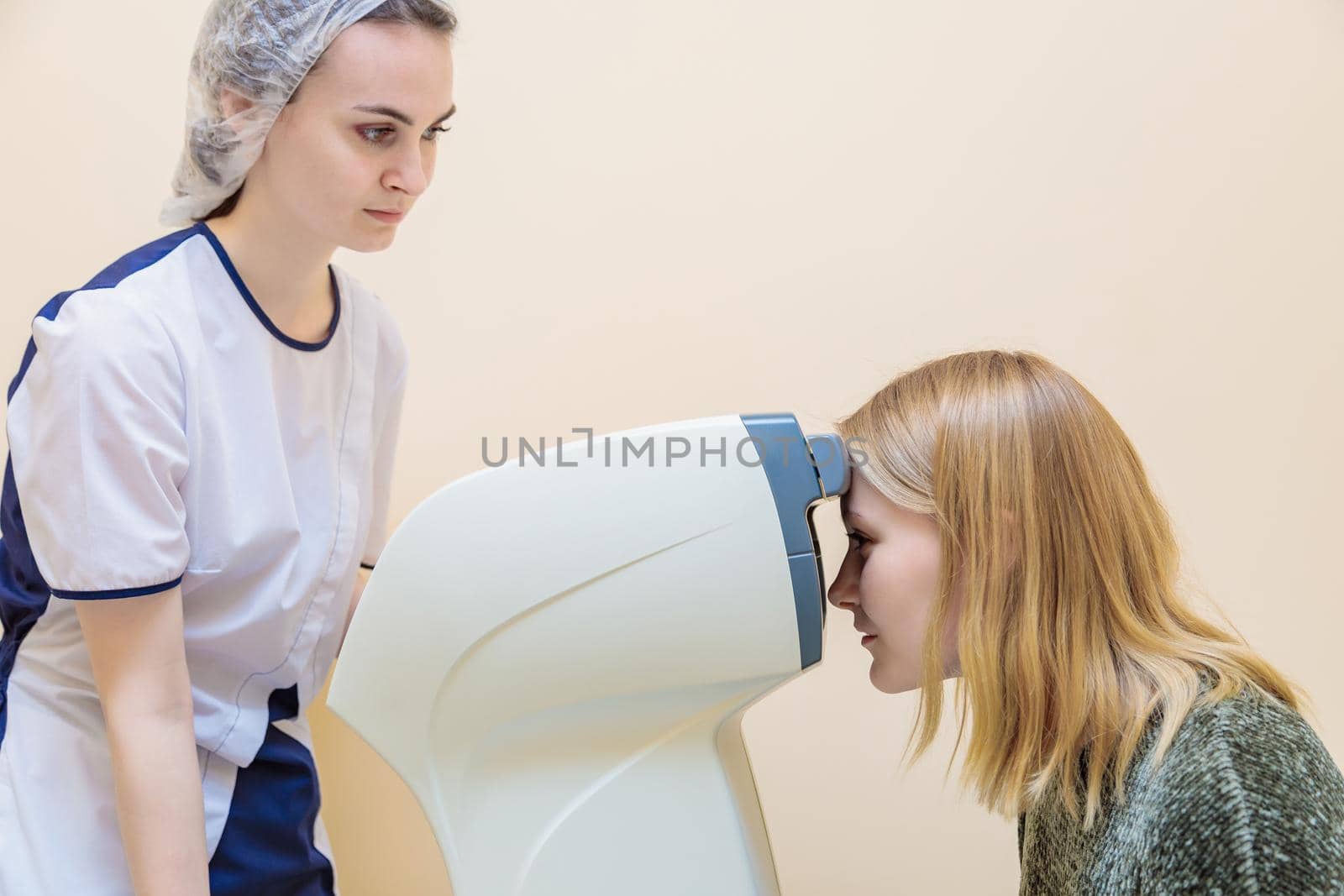A girl optometrist examines the eyes of a patient using special modern equipment.