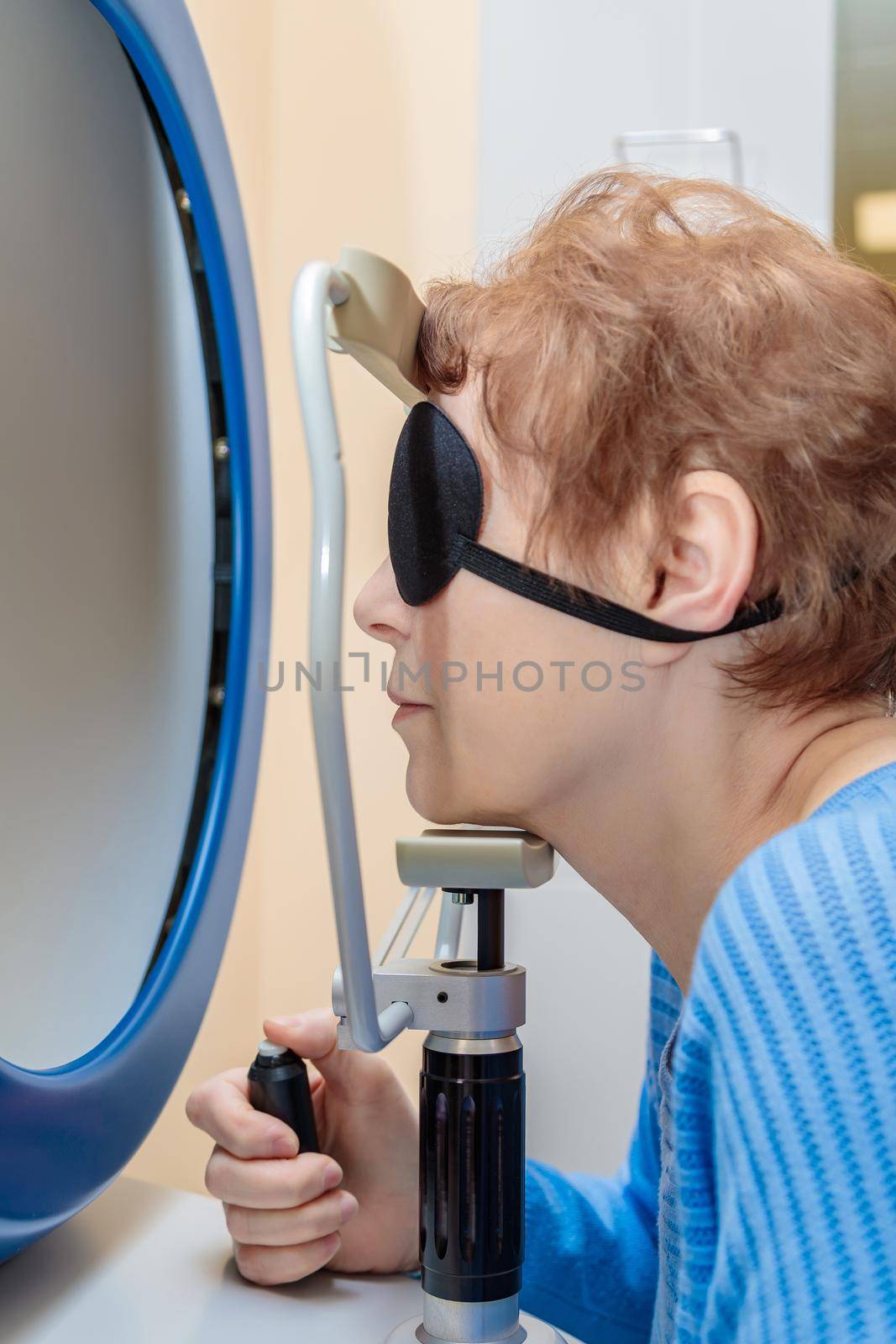 An adult girl at an ophthalmologist's appointment checks her eyesight on a special apparatus. Close-up.