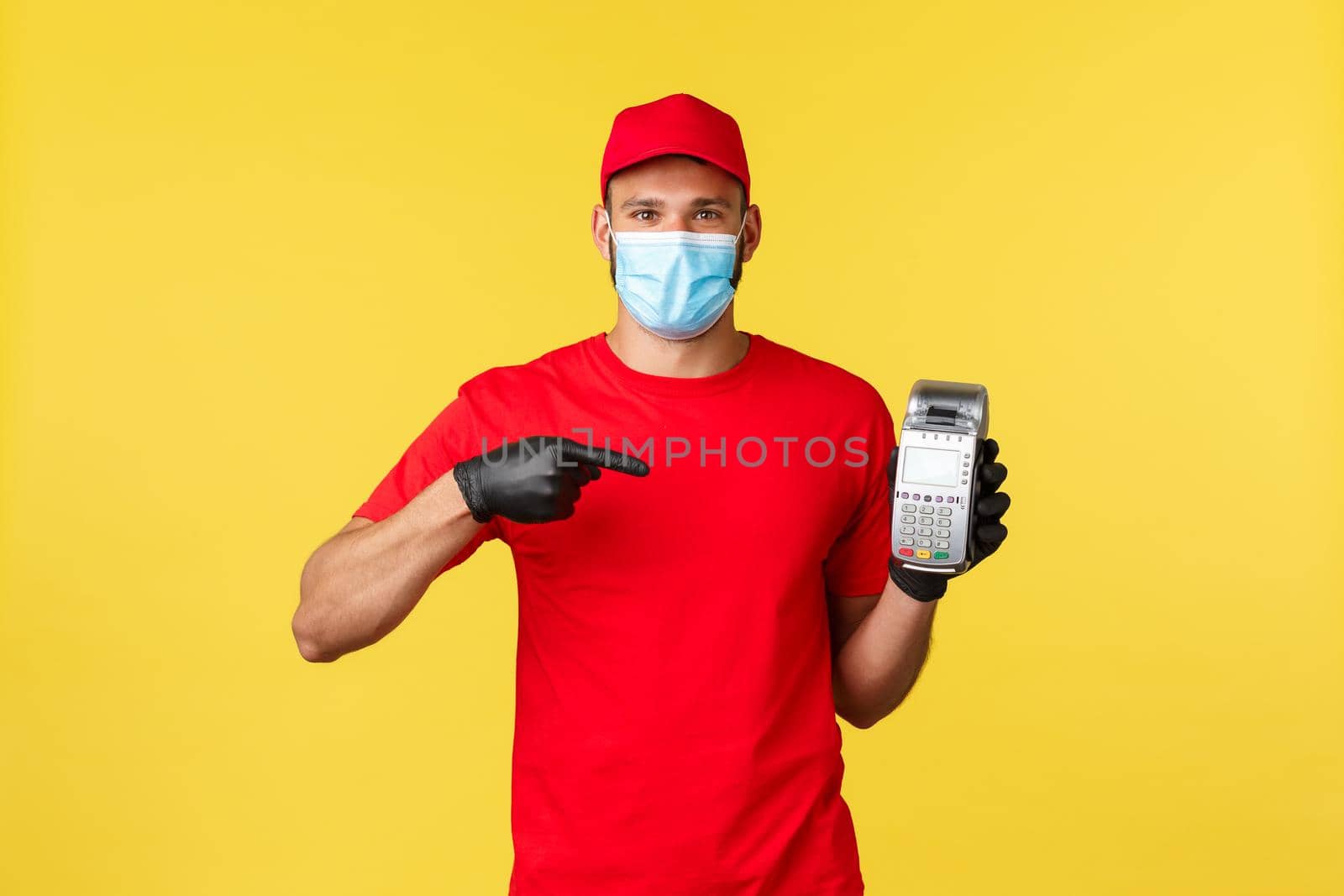 Food delivery, tracking orders, covid-19 and self-quarantine concept. Courier recommends using POS terminal for safe contactless paying during coronavirus pandemic, yellow background.