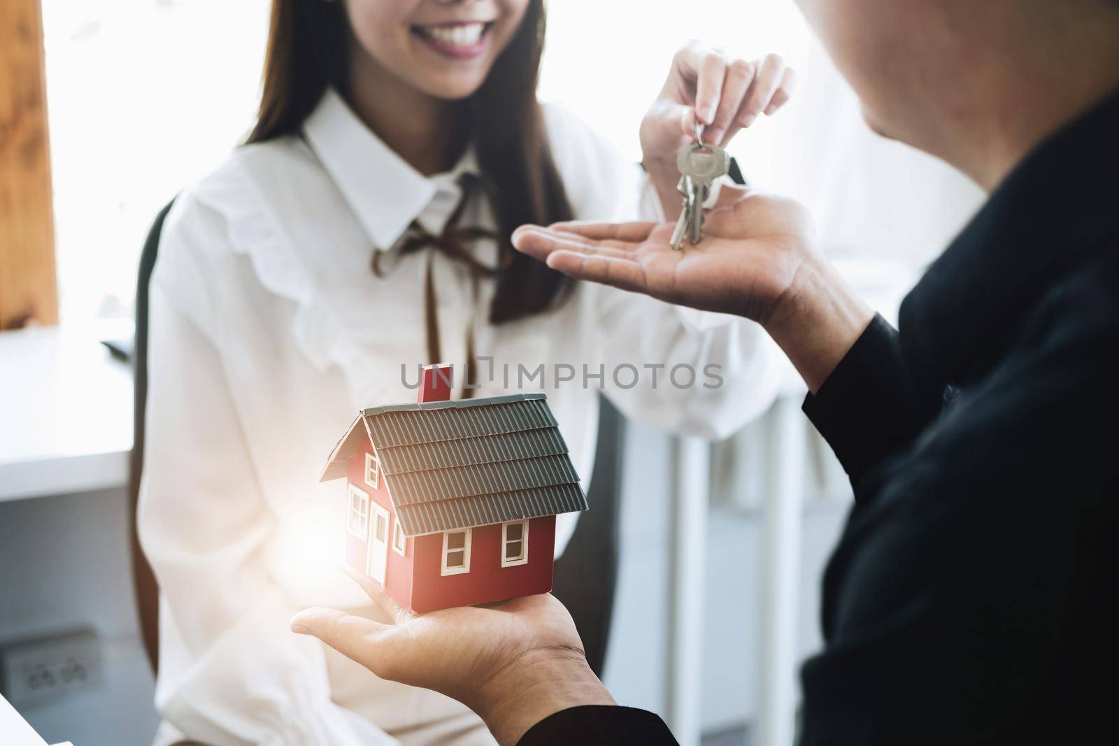 guarantees, mortgages, contract and agreement, focus model house of real estate agents are holding the keys to the customers after the contract for the sale of land and buildings is completed. by Manastrong