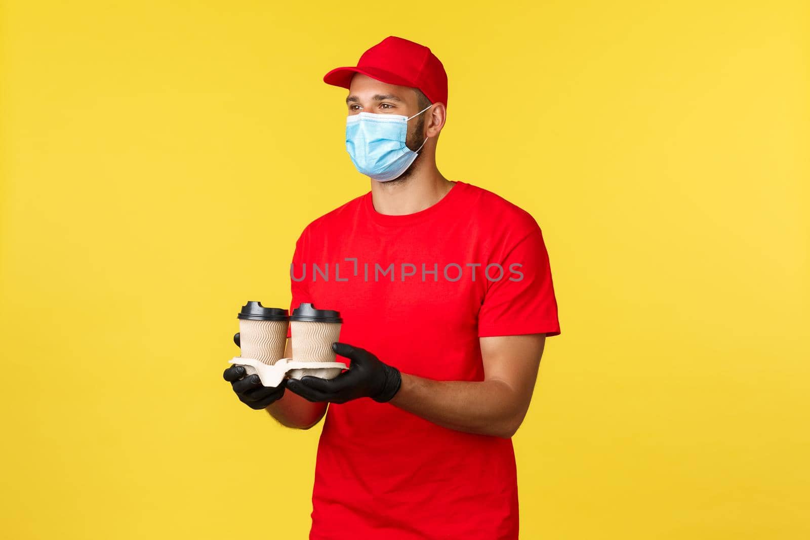 Takeaway delivery, food and drinks, covid-19 quarantine and preventing virus concept. Nice smiling courier bring order, drive through employee handing coffee to customer, wear medical mask.