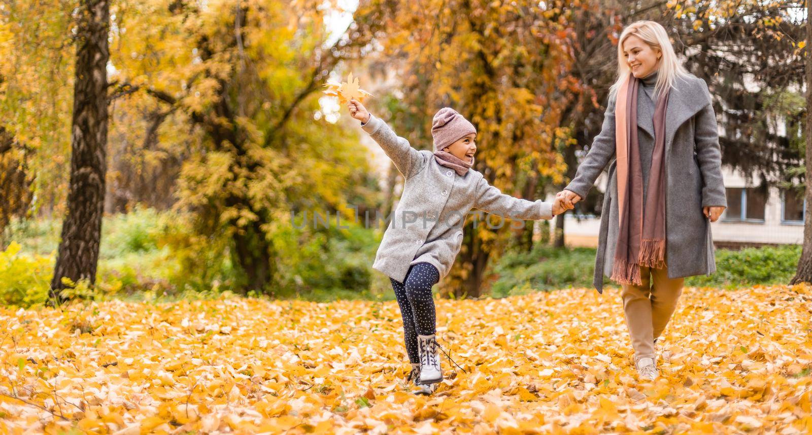 Mother and daughter in autumn yellow park.