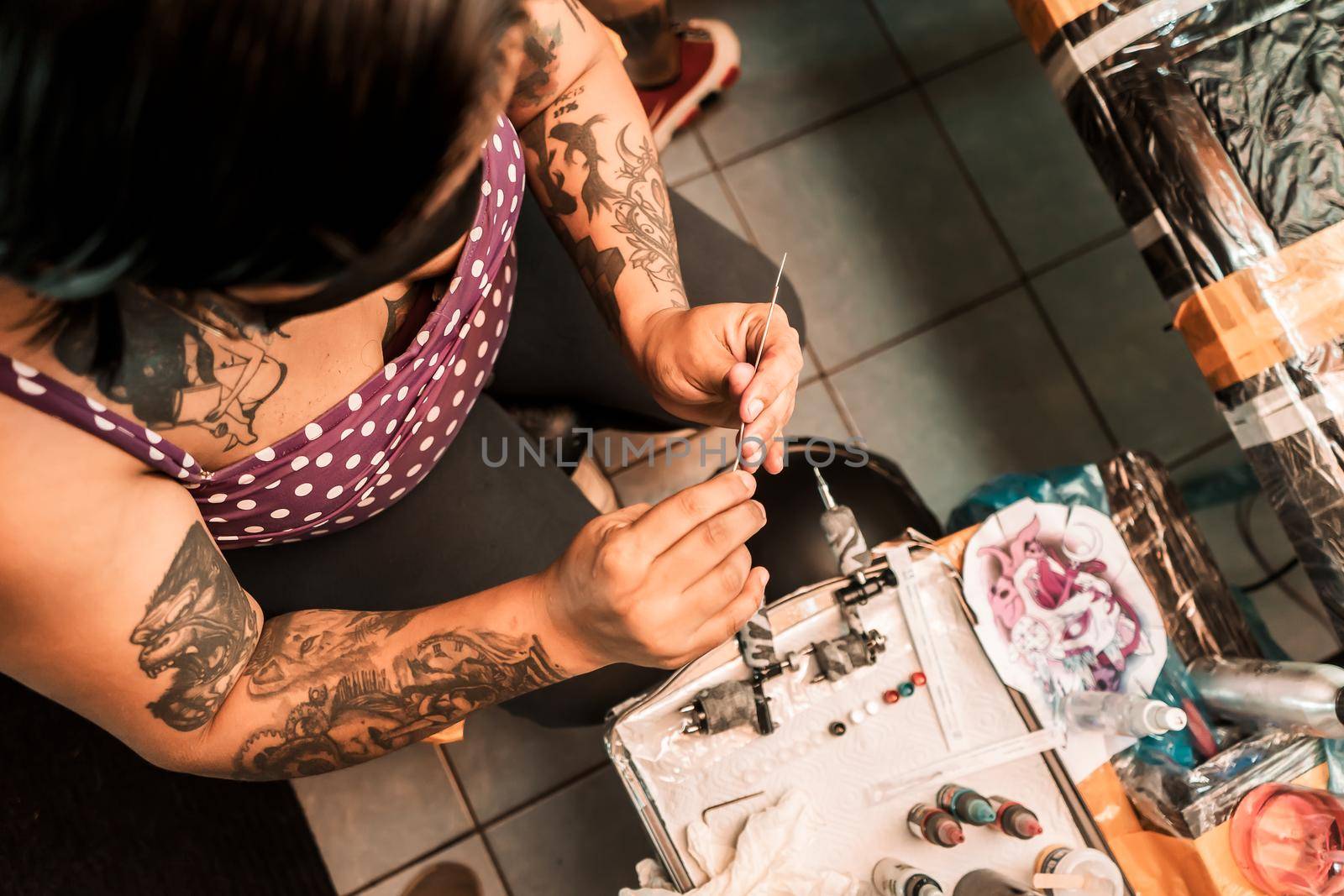 Latina tattoo artist preparing needles to work on a client's skin in a salon in Nicaragua by cfalvarez