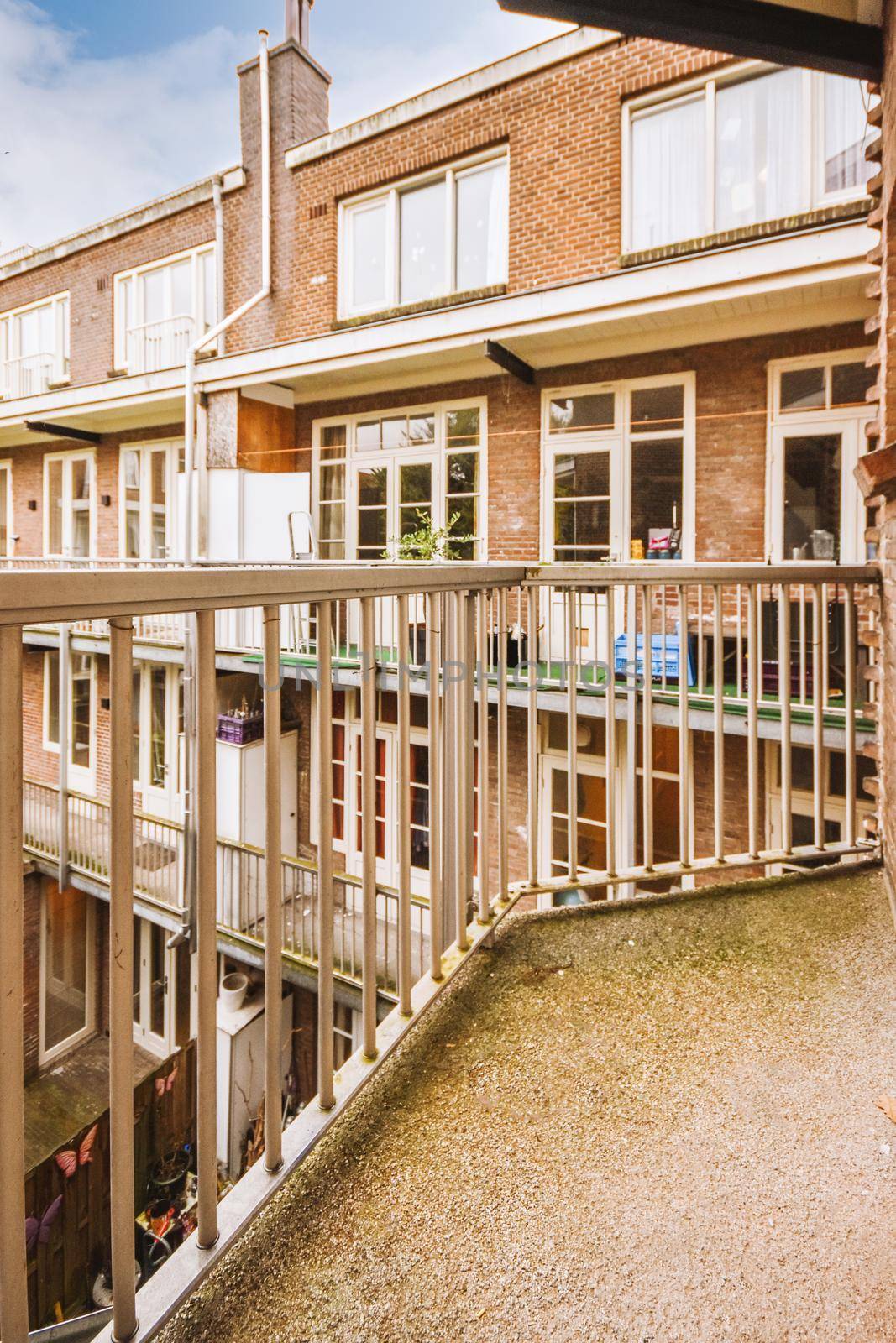 Panoramic view of old brick buildings with parking and trees from small balcony