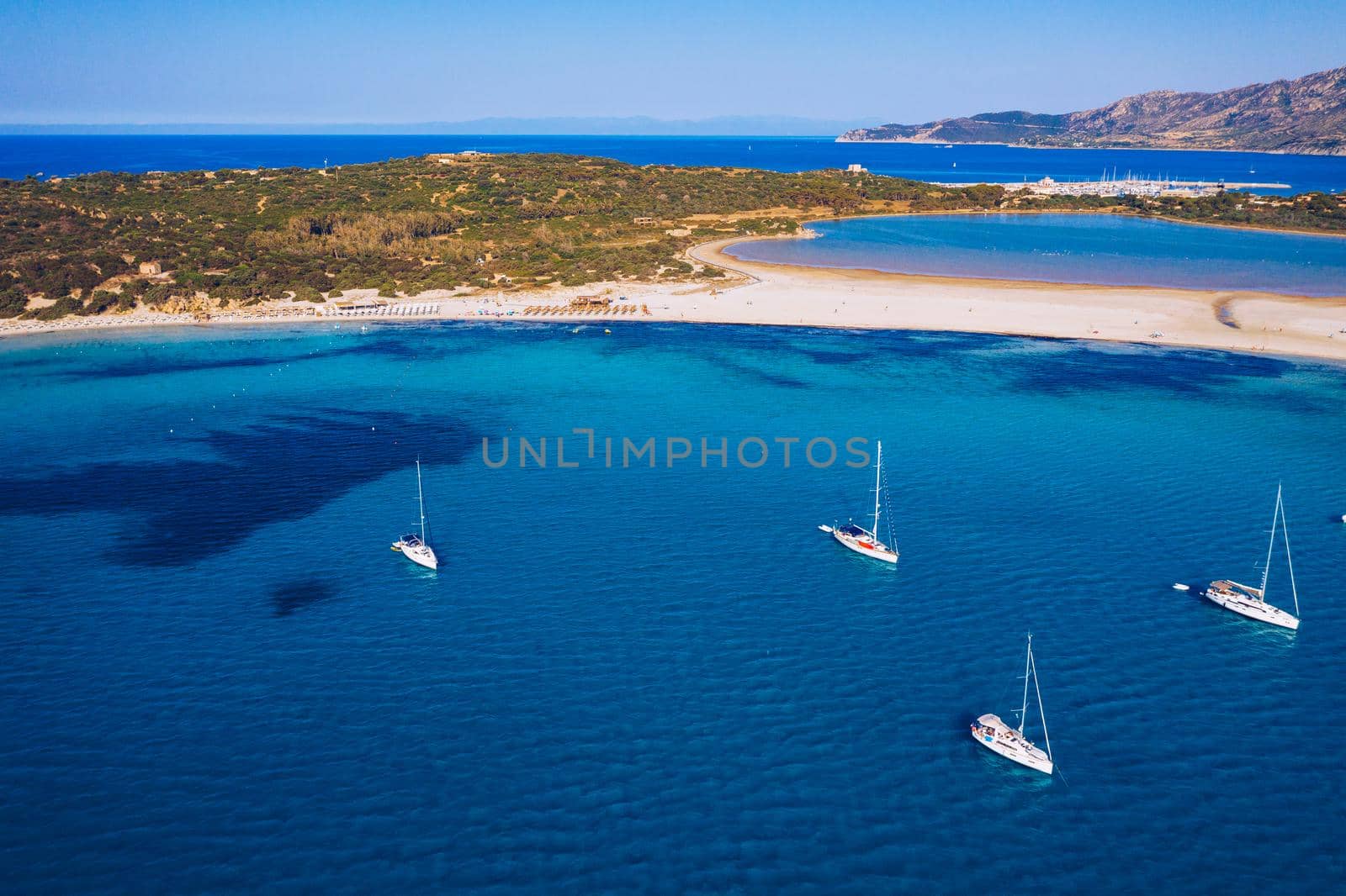 Yacht anchoring in crystal clear turquoise water in front of the tropical island, alternative lifestyle, living on a boat. Aerial view of yacht at anchor on turquoise water, showing luxury, wealth.